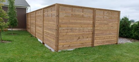 A wooden fence is sitting in the middle of a lush green yard.