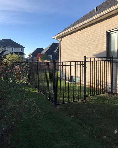There is a black fence in the backyard of a house.