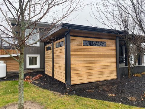 A wooden shed is sitting in front of a house.