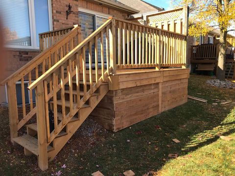 A wooden deck is in the backyard of a house.