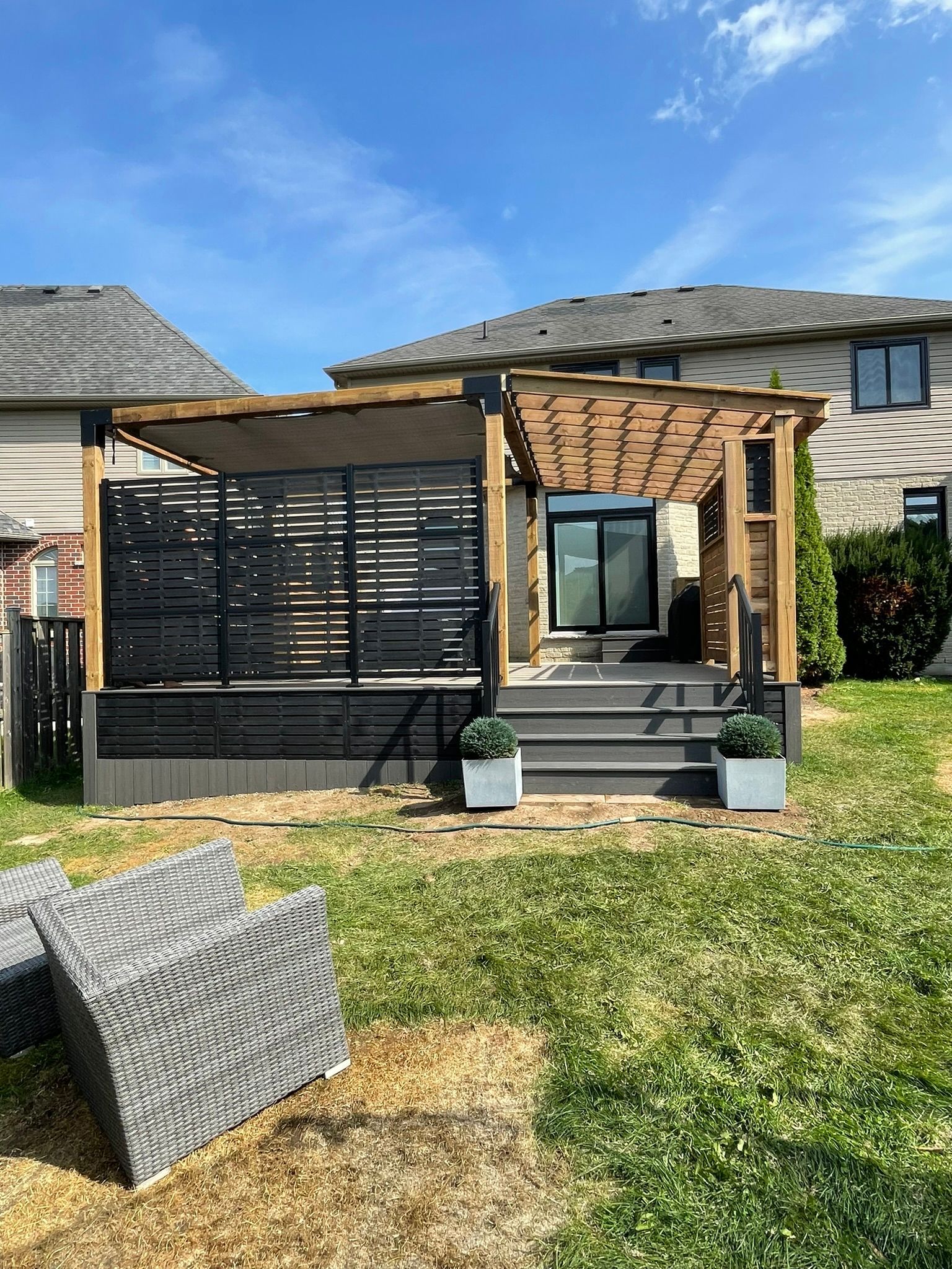 There is a pergola in the backyard of a house.