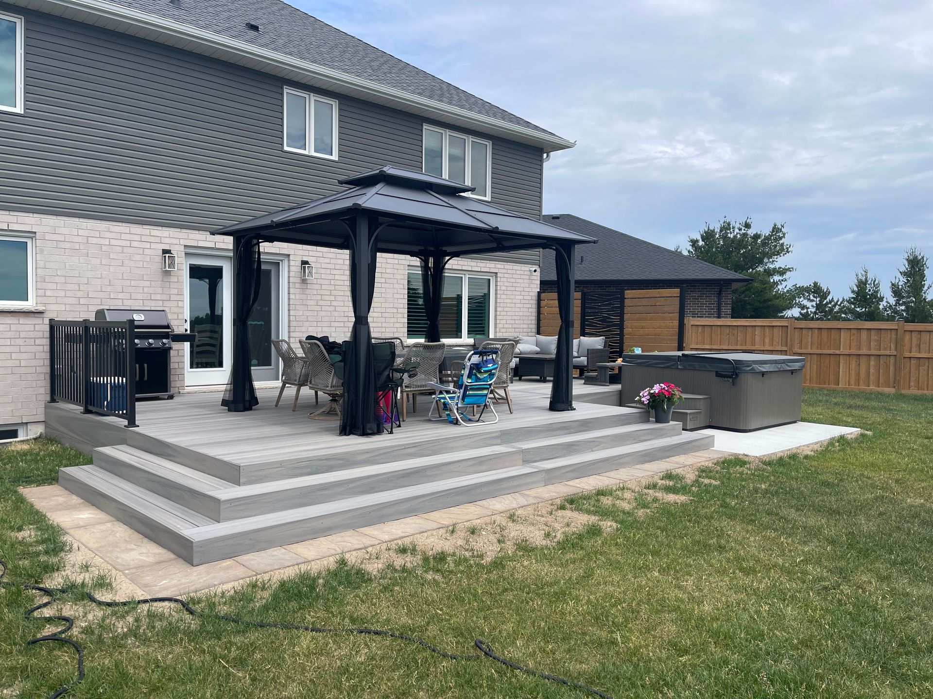 A large patio with a gazebo and a hot tub in the backyard of a house.