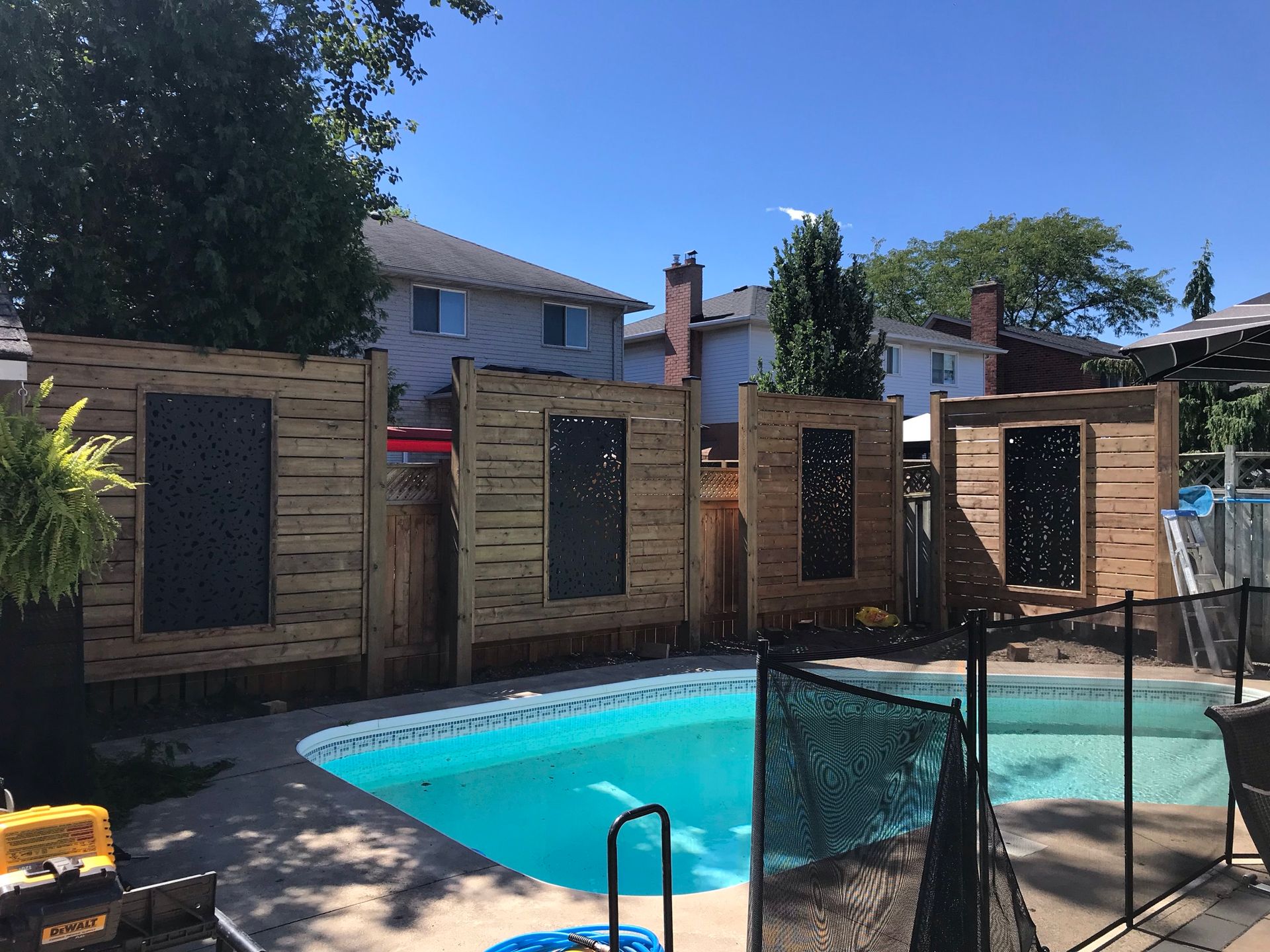 A fence surrounds a swimming pool in a backyard.
