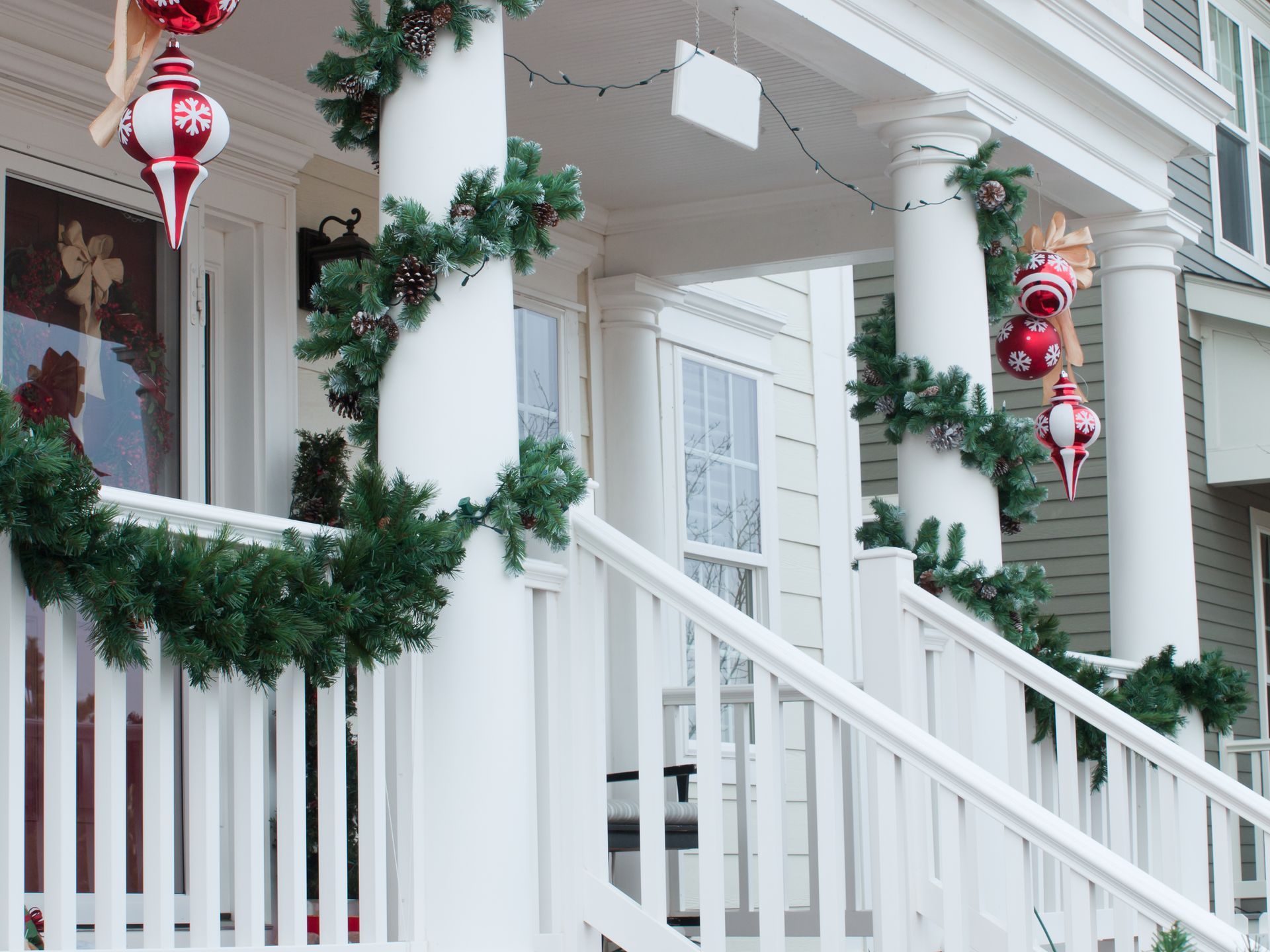 Festive house exterior with garland and ornaments on the porch, white railing, and columns.