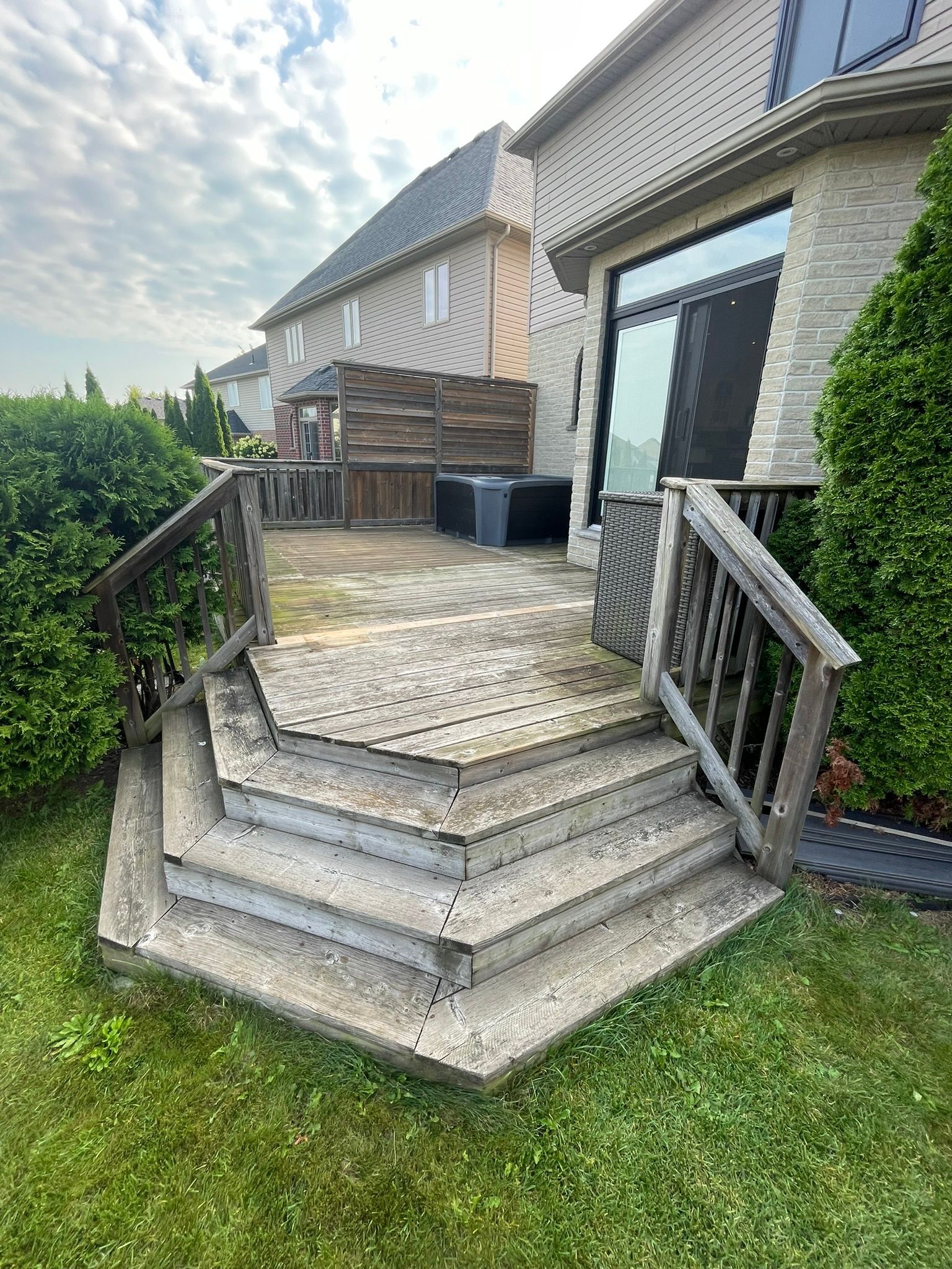 A wooden deck with stairs leading up to it in front of a house.