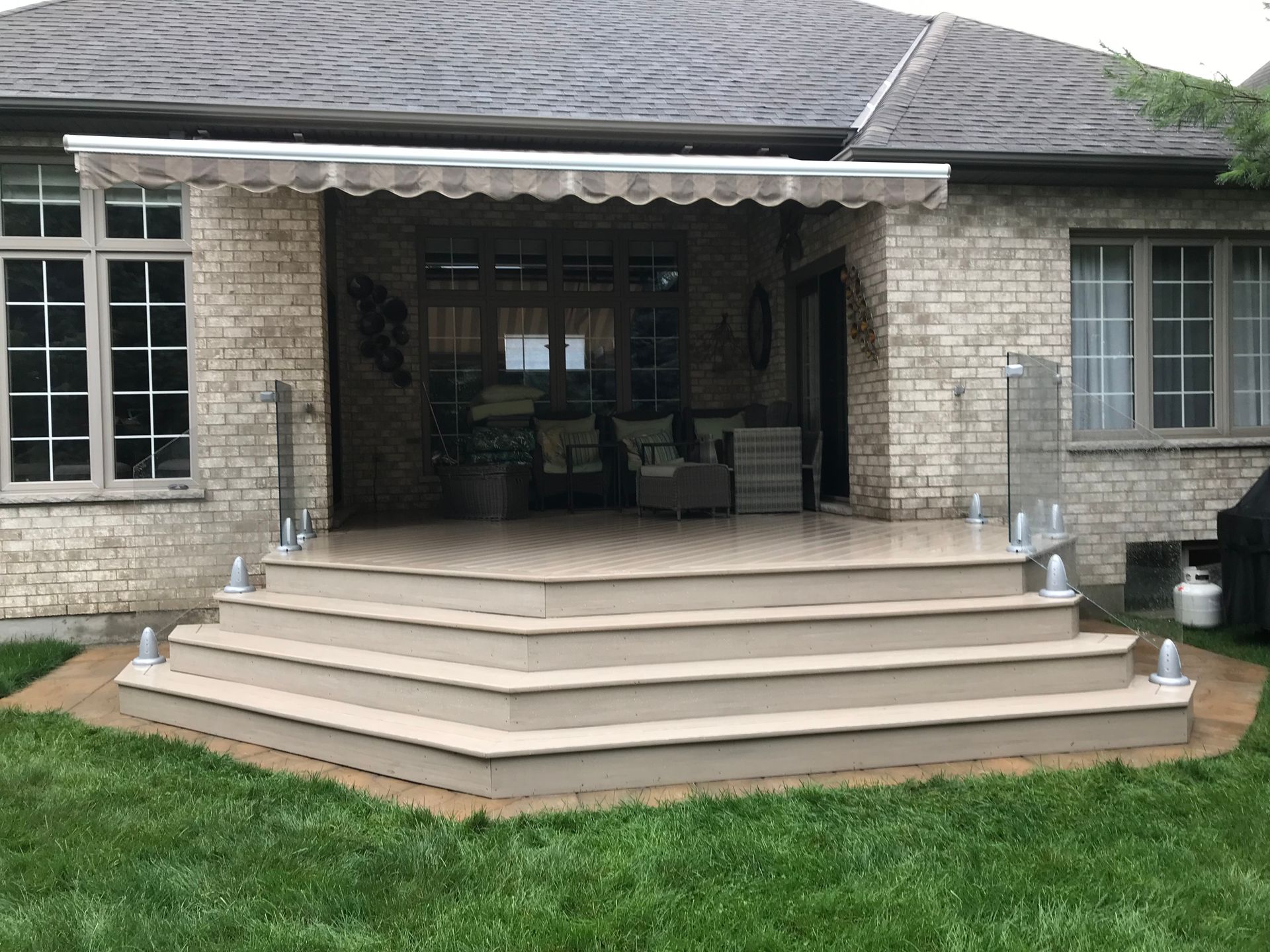 A brick house with a deck and stairs in front of it.