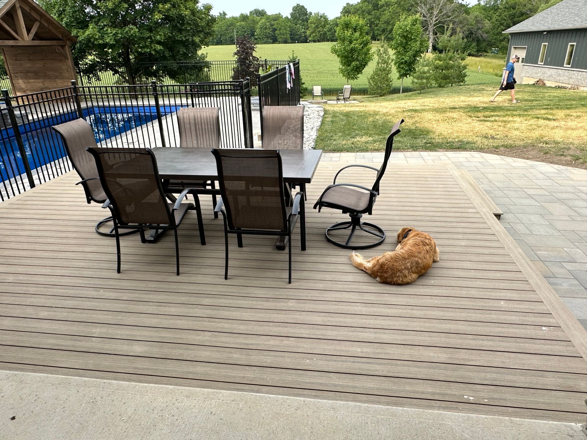 A dog is laying on a patio next to a table and chairs.