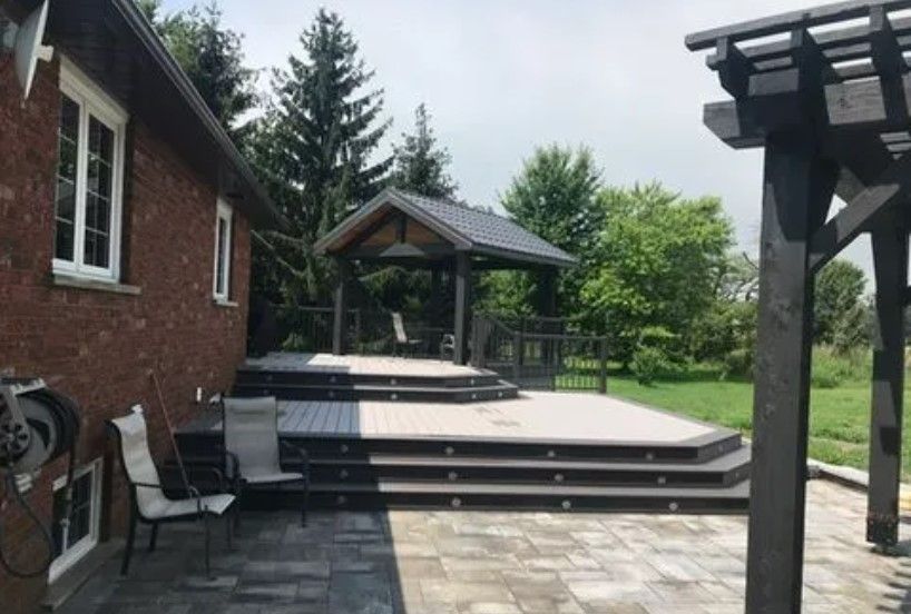 Brick house with multi-level wooden deck, pergola, and outdoor seating.