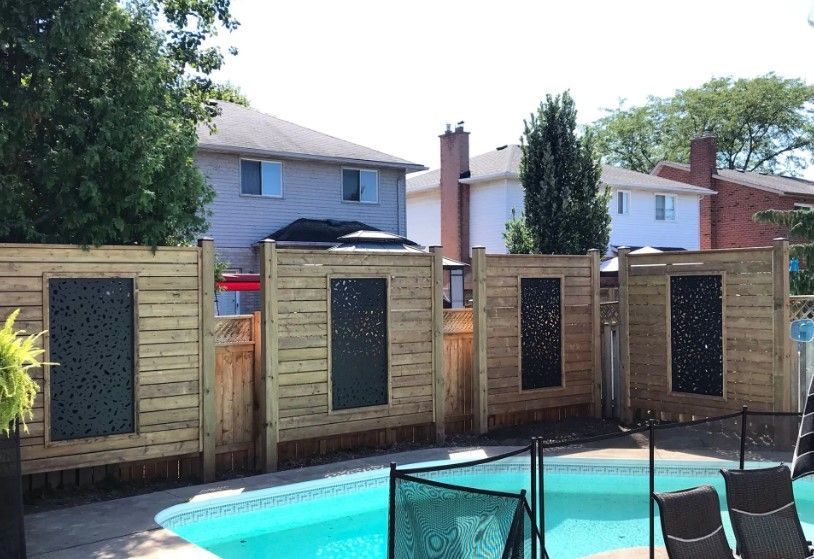 Wooden fence with decorative panels surrounds a backyard pool.