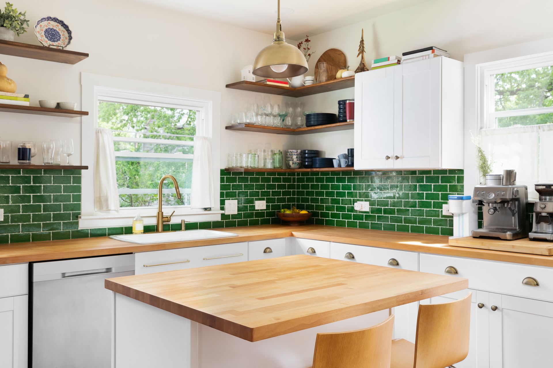 Bright kitchen with green tile backsplash, white cabinets, wooden countertops, and a central island