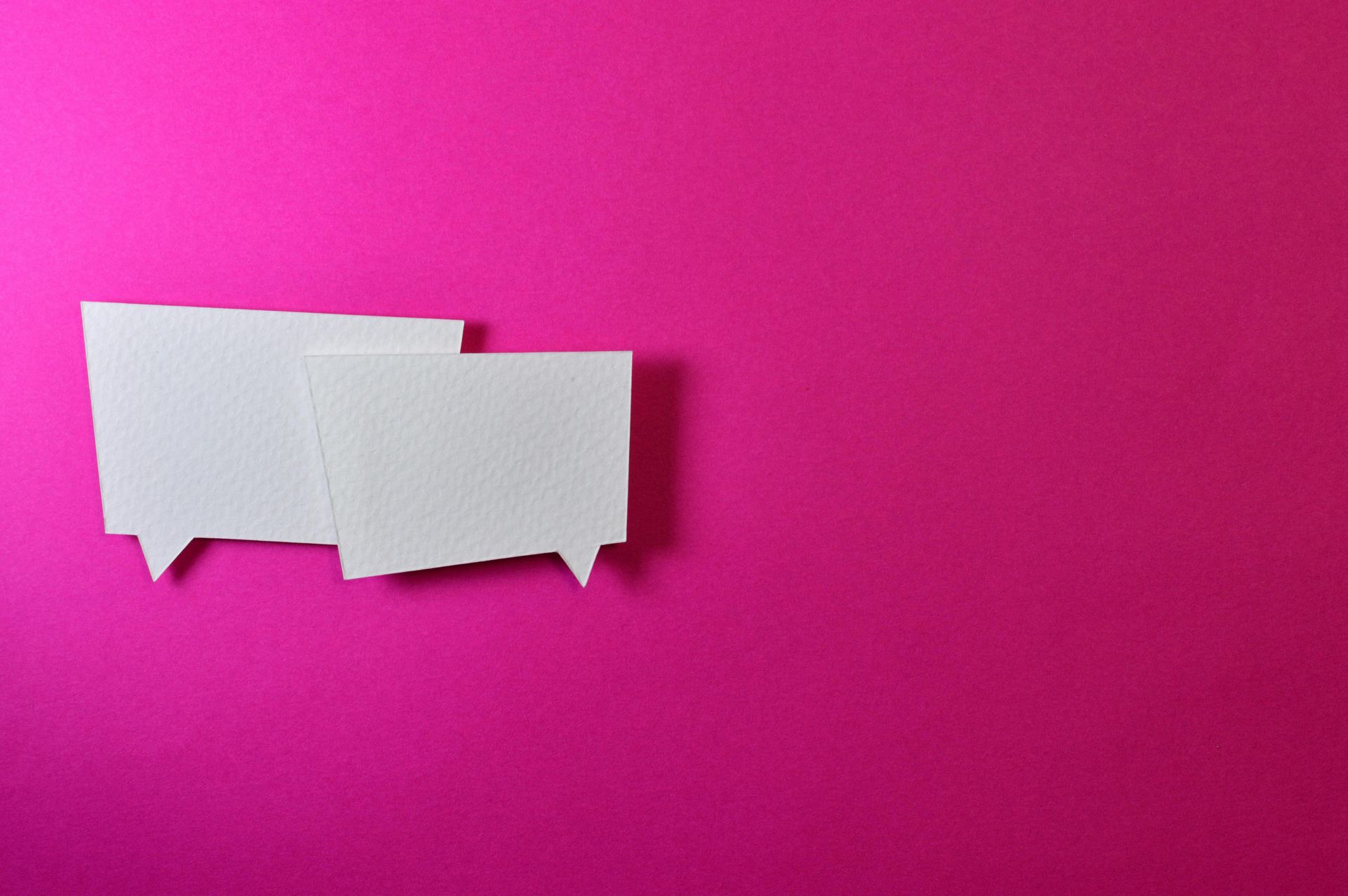 Two white speech bubbles on a pink background.