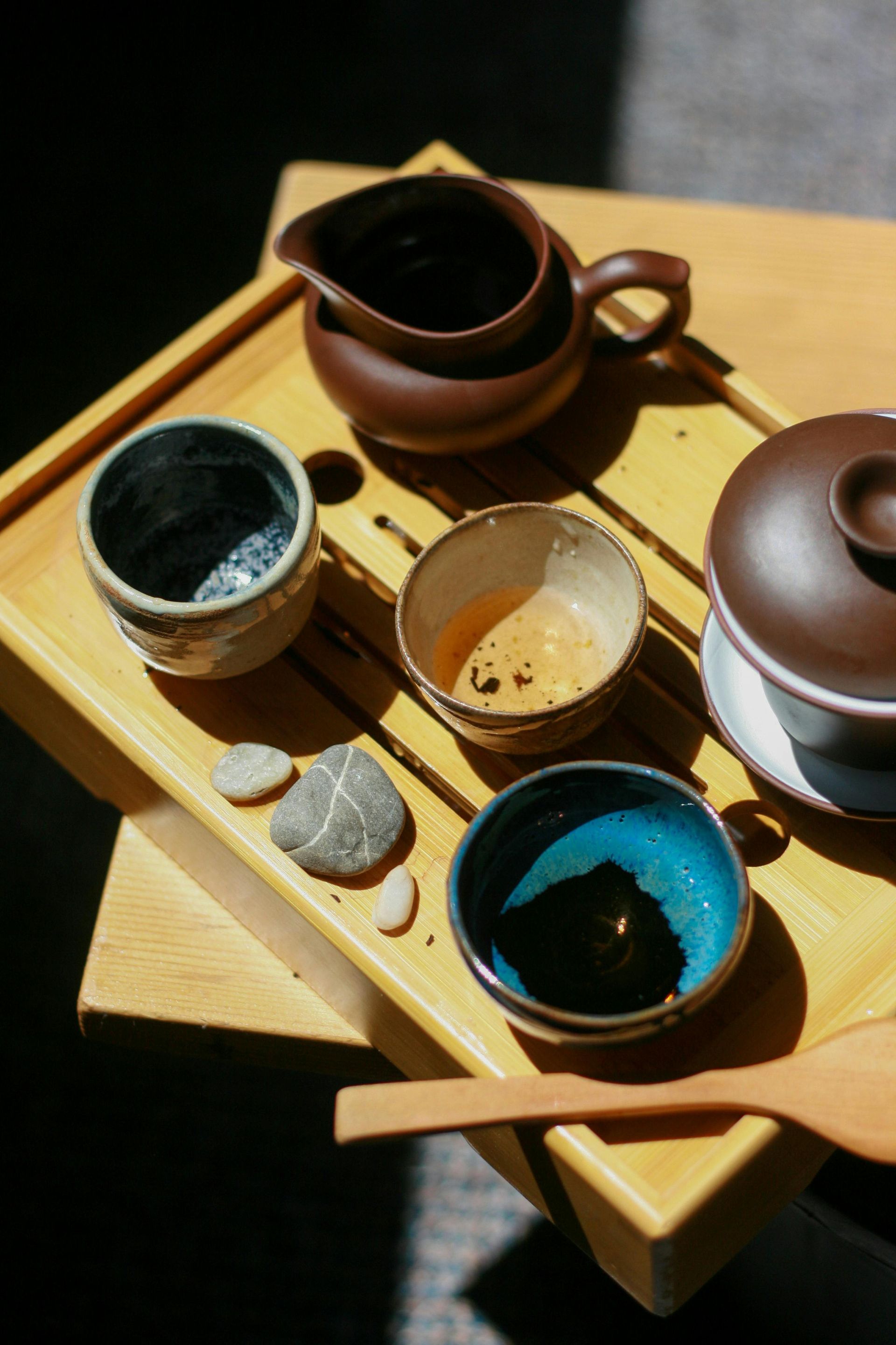 A wooden tray with bowls of tea and a pitcher on it.