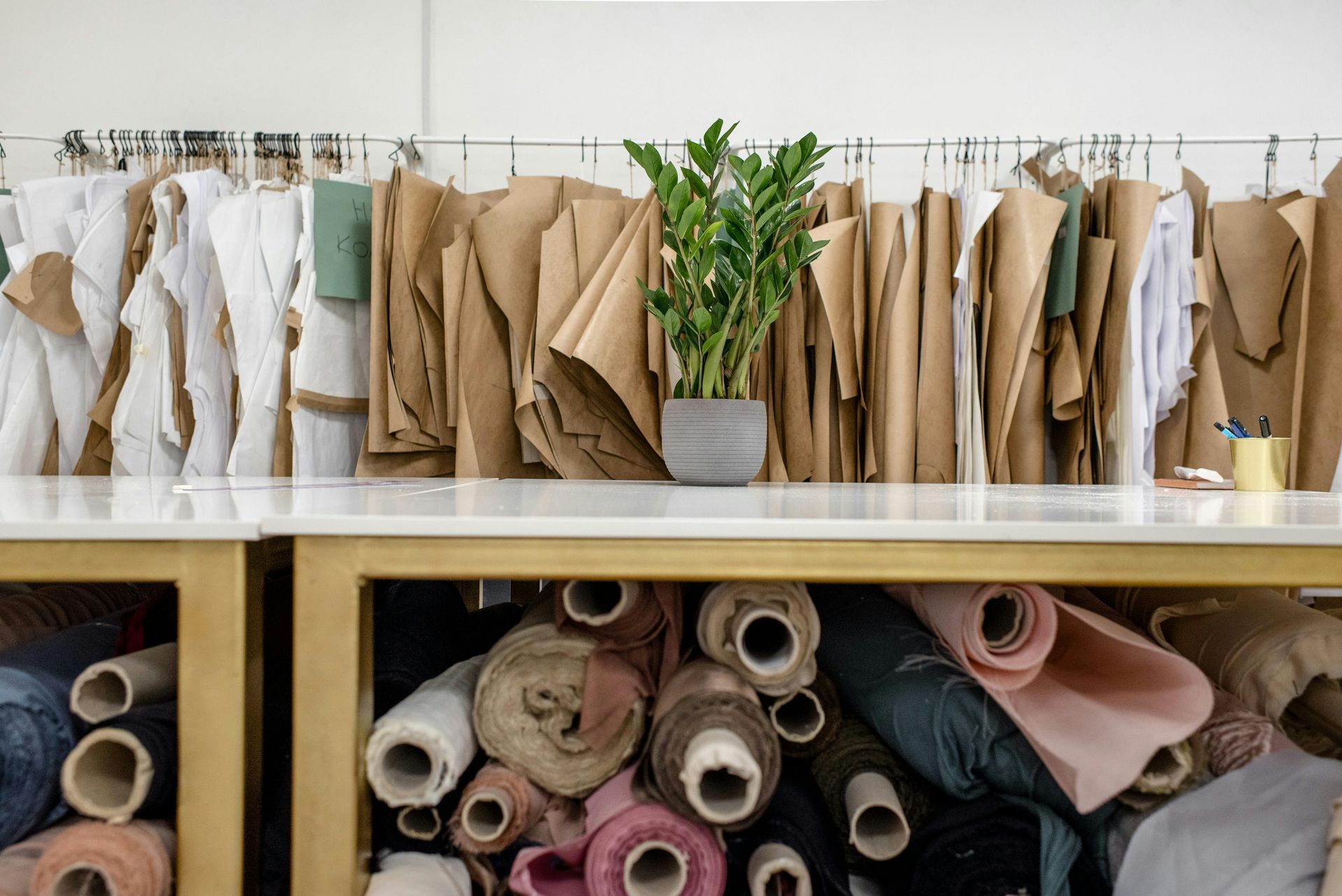 A table filled with rolls of fabric and a plant.