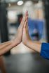 Two people are giving each other a high five in a gym.