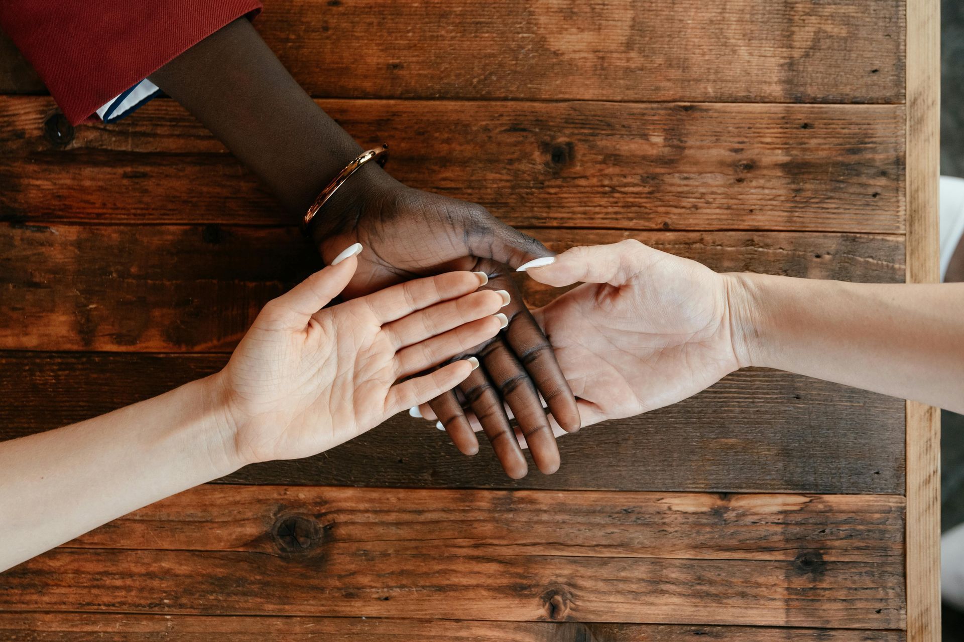 A man and a woman are holding hands on a wooden table.