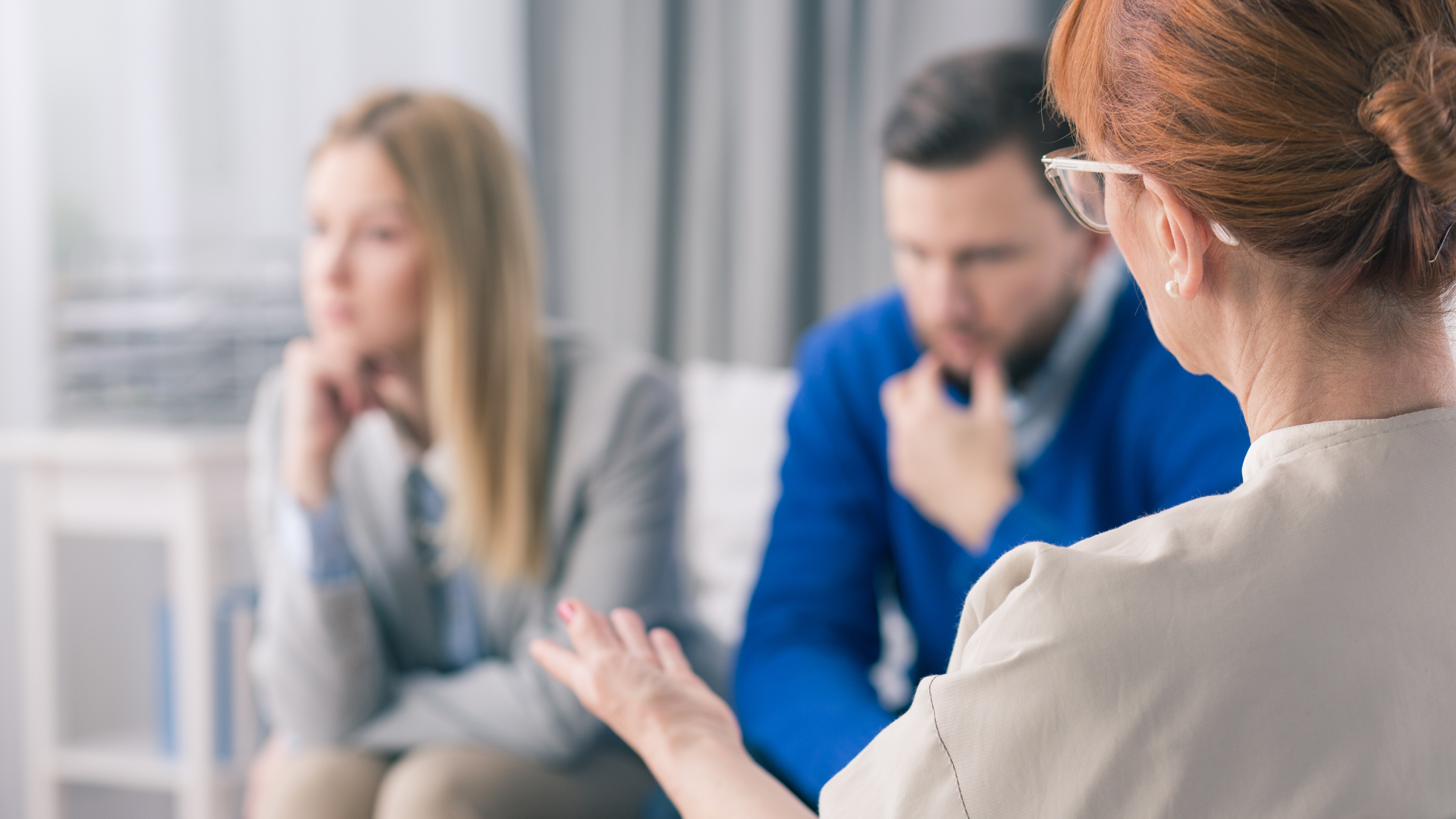 A couple in counseling, looking concerned, while a therapist gestures.