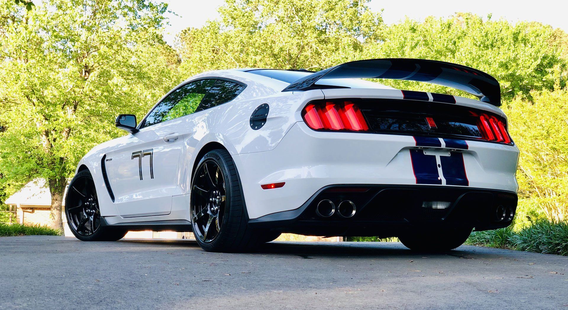 A white ford mustang is parked on the side of the road.