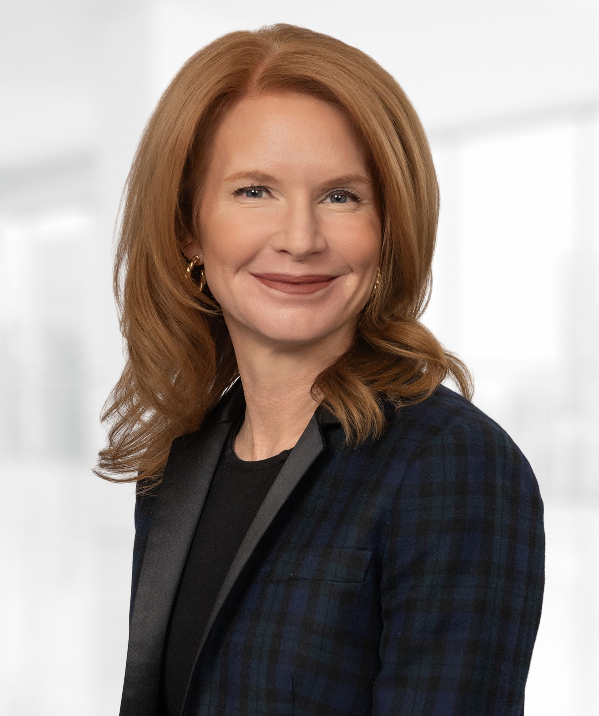 A woman with red hair is smiling and wearing a blue jacket