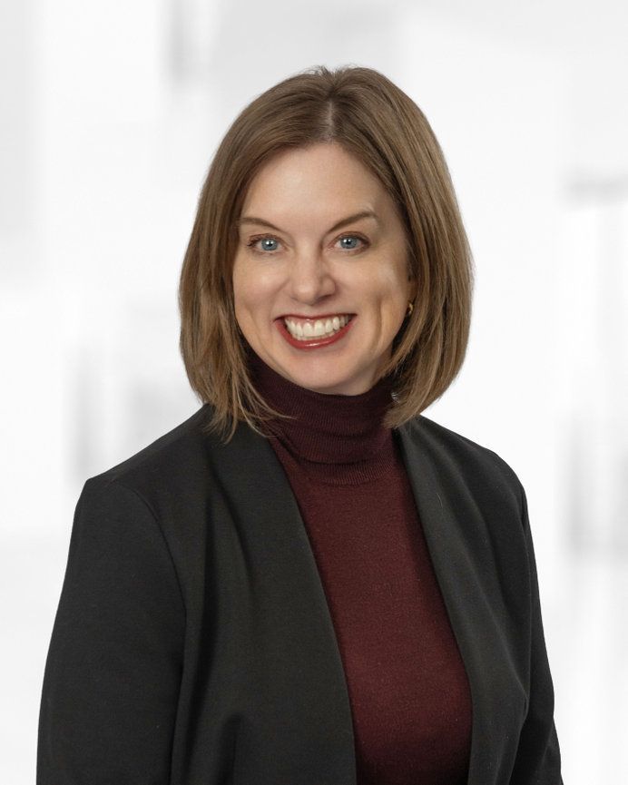 A woman in a black jacket is smiling for the camera.