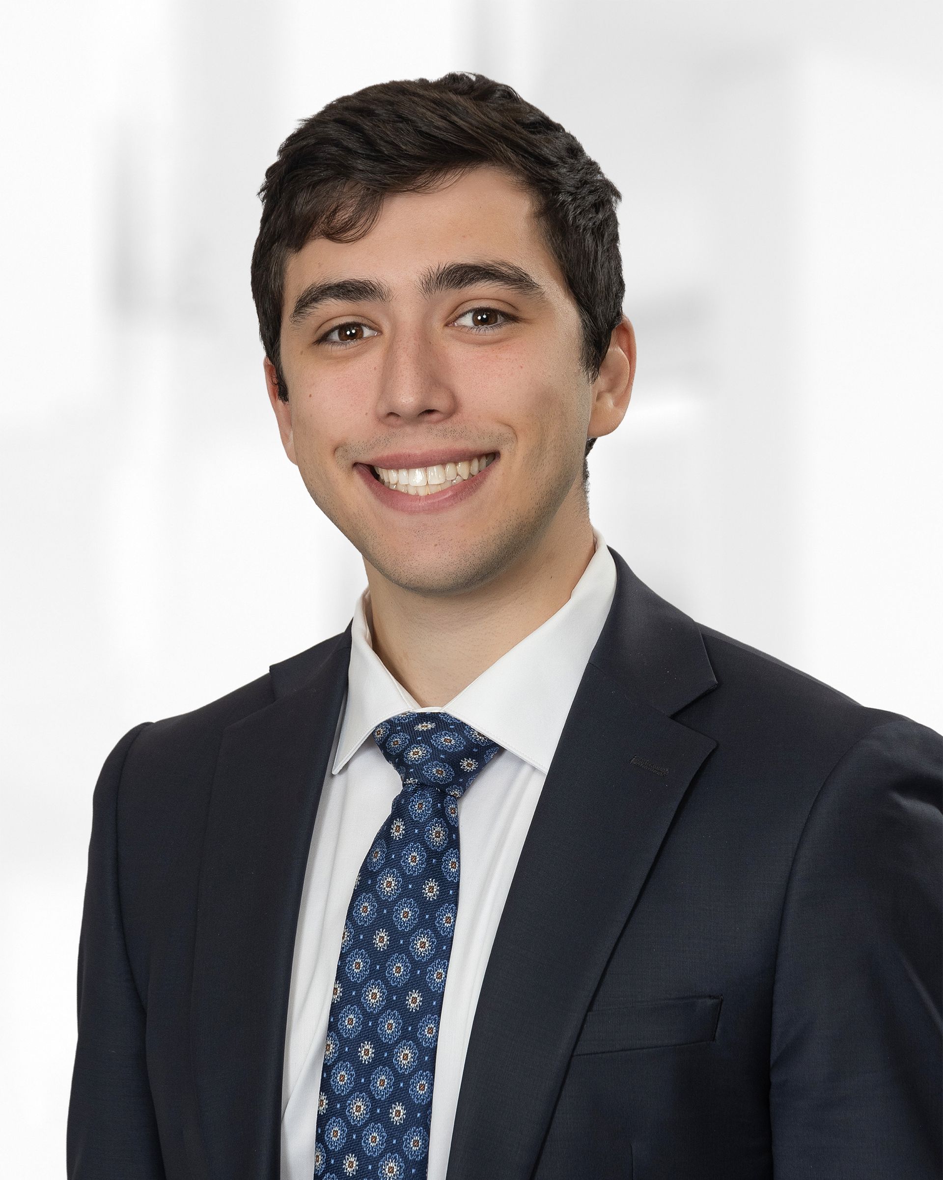 A woman wearing a suit and a pearl necklace smiles for the camera.