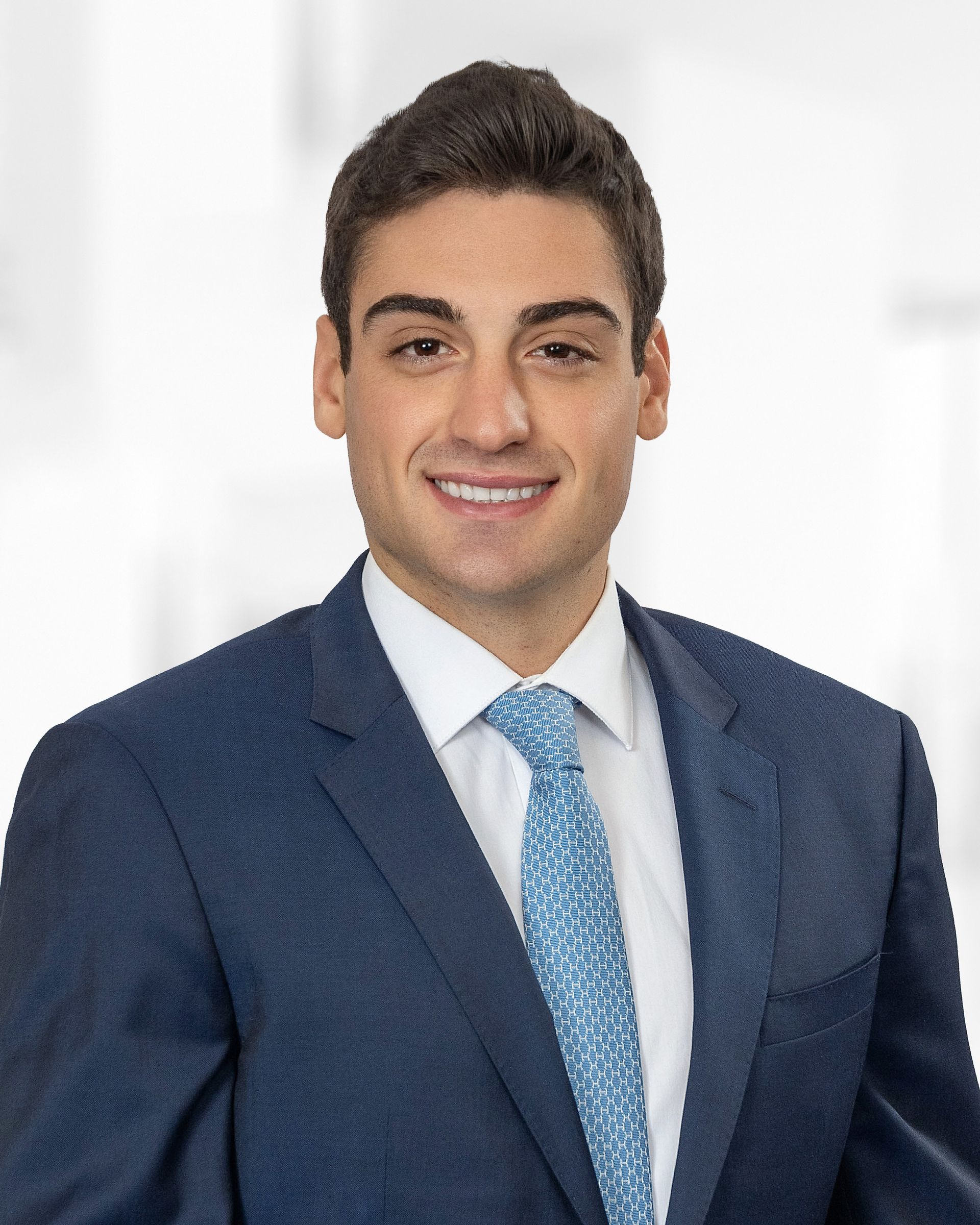 A woman wearing a suit and a pearl necklace smiles for the camera.
