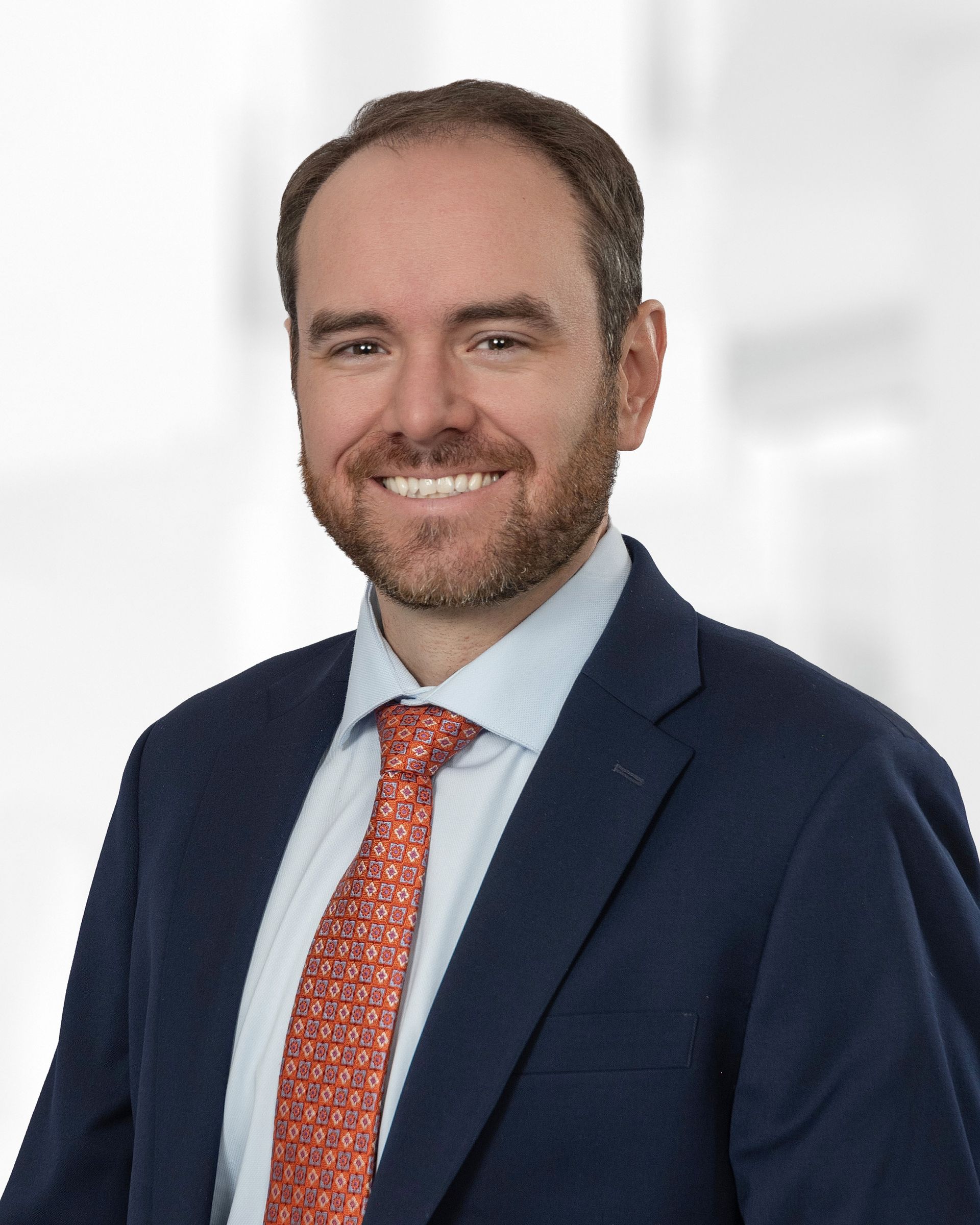 A woman wearing a suit and a pearl necklace smiles for the camera.