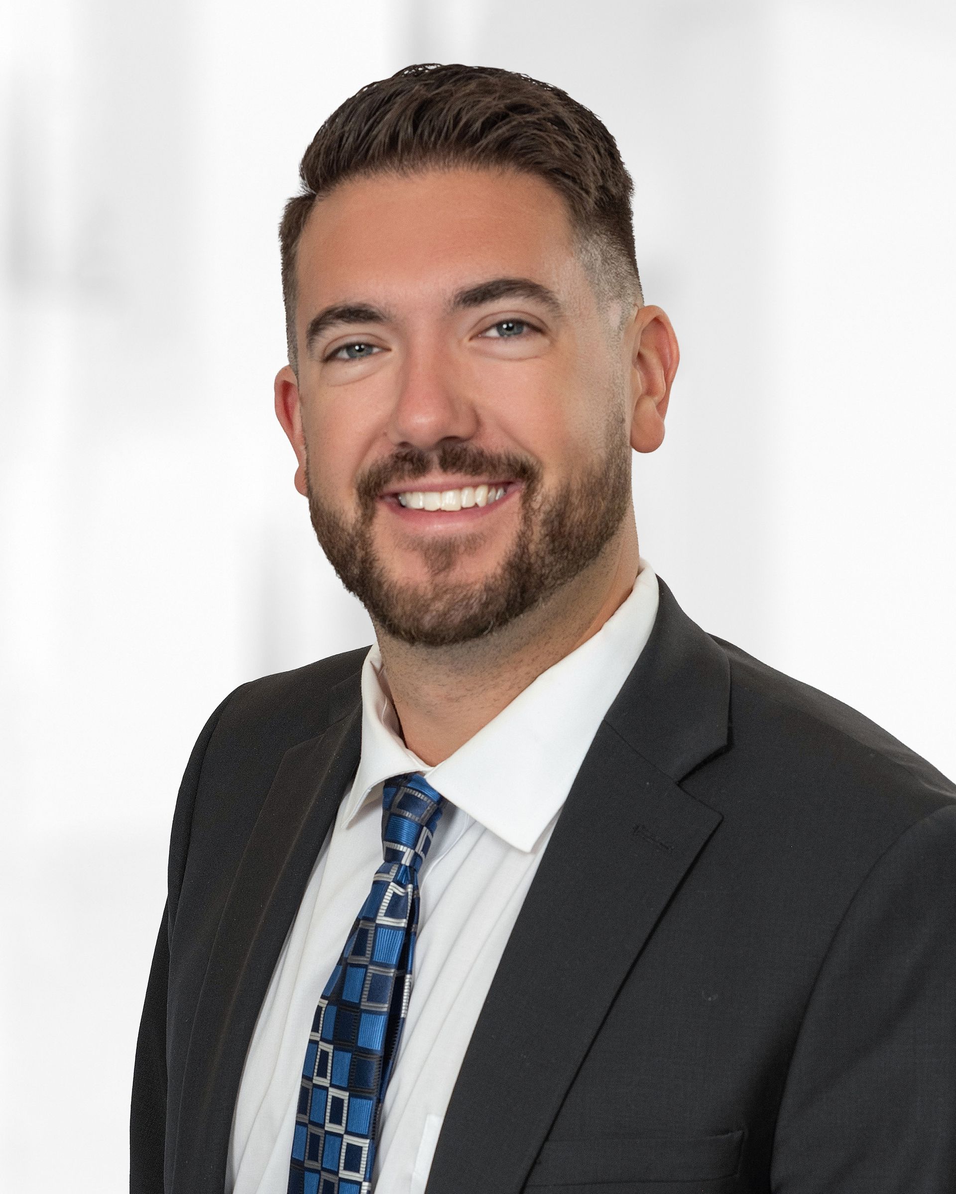A woman wearing a suit and a pearl necklace smiles for the camera.