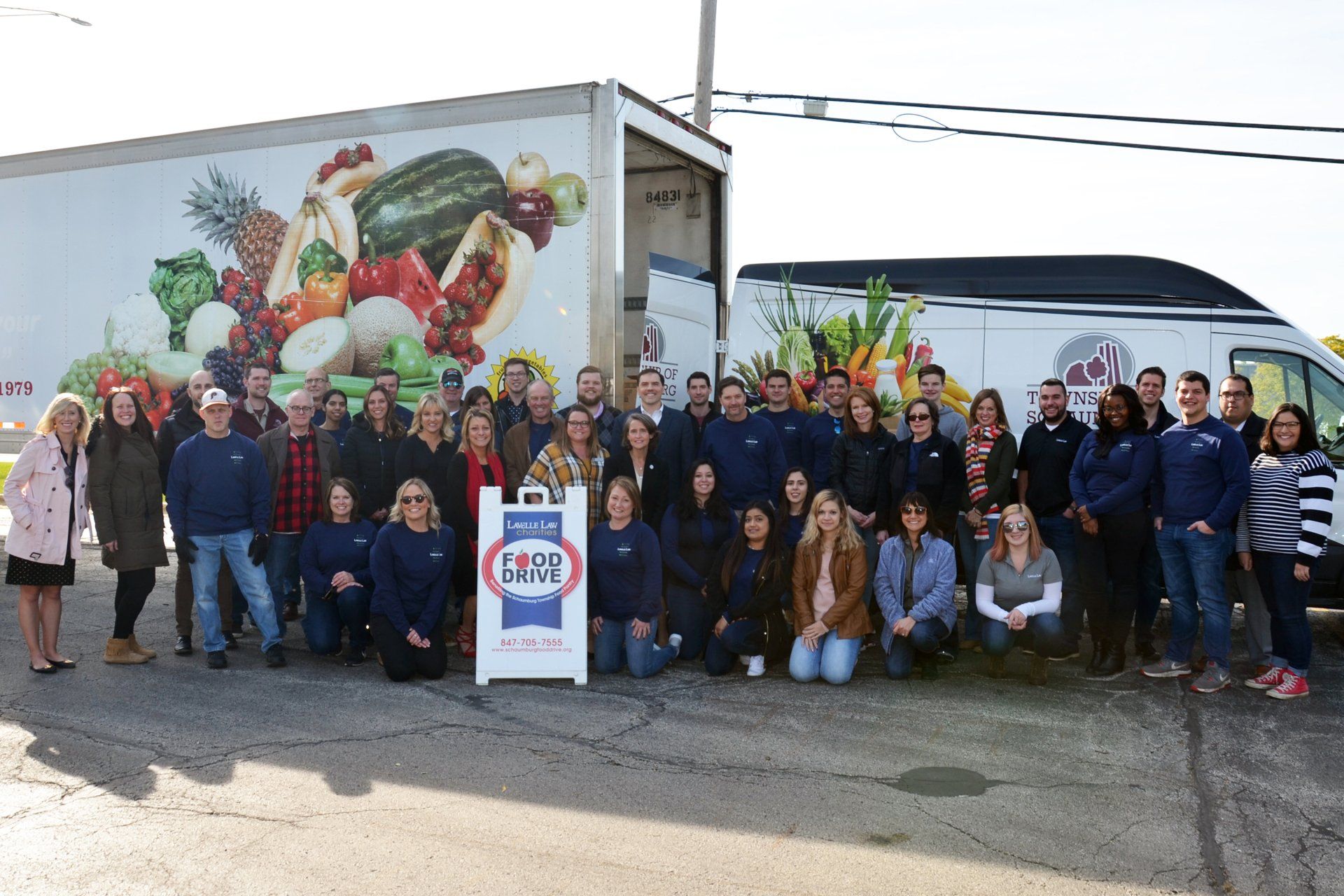 A group of people are posing for a picture in front of a truck.