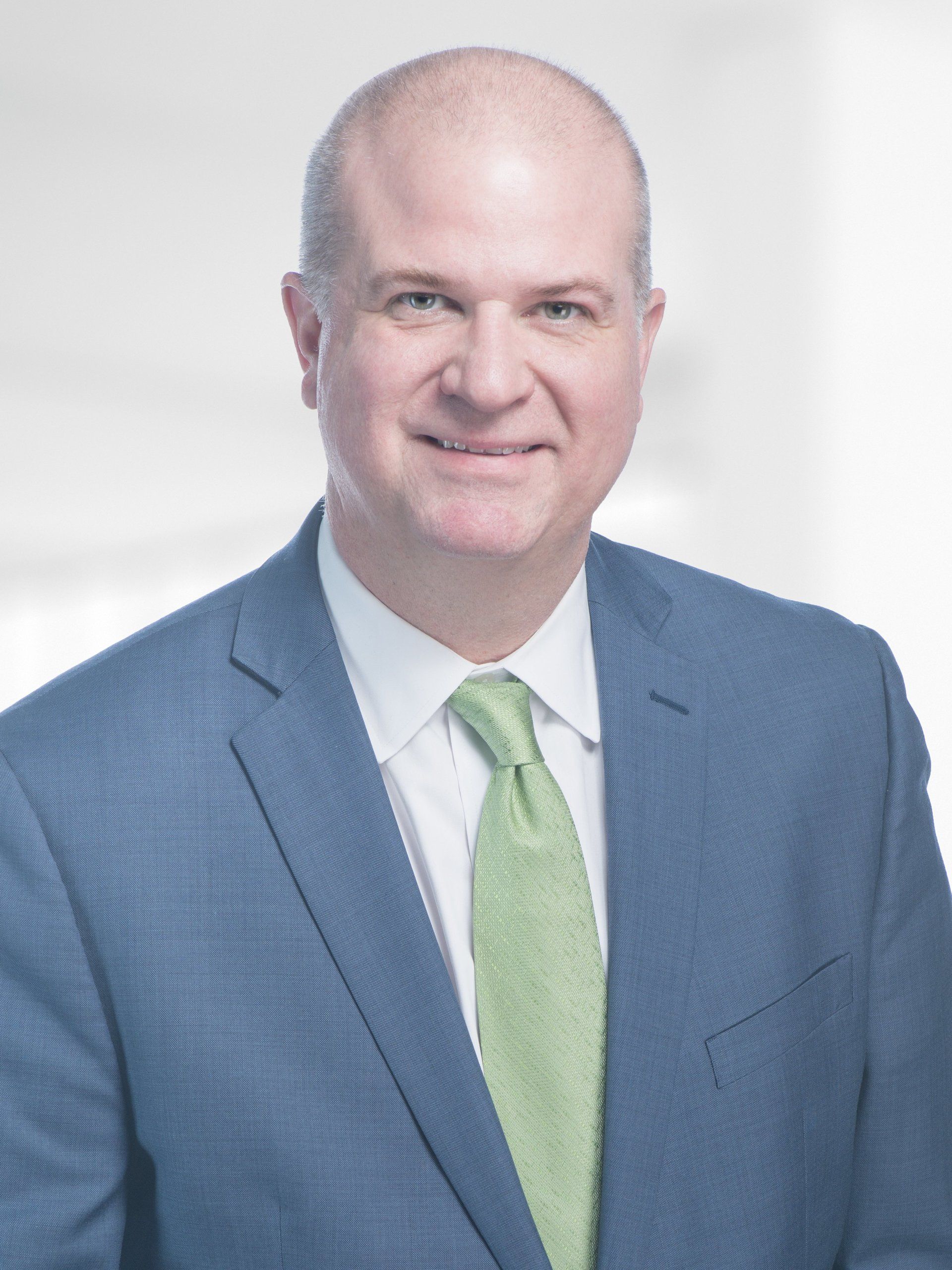 A man in a blue suit and green tie is smiling for the camera.
