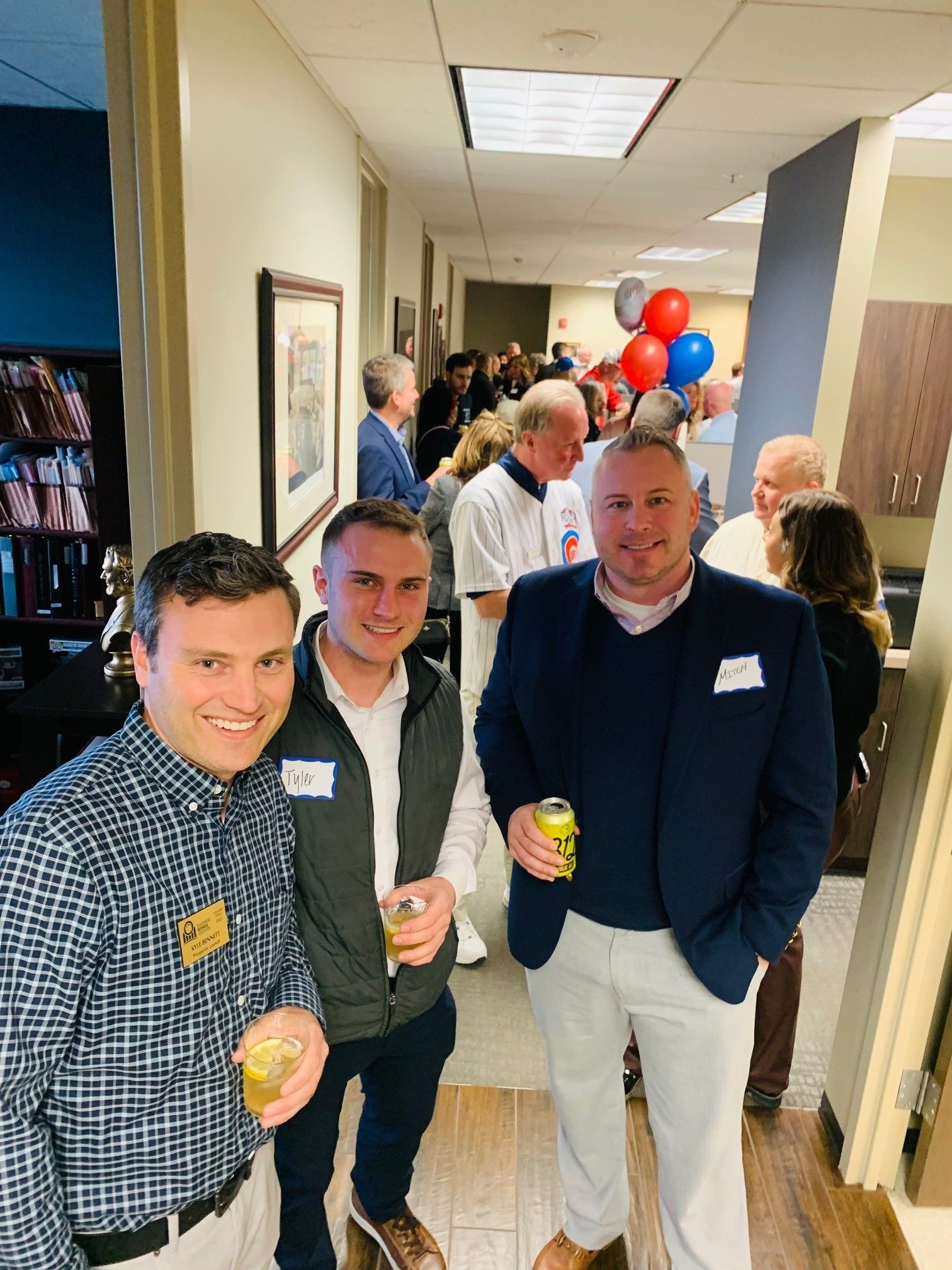 A group of men are standing in a hallway with balloons in the background.