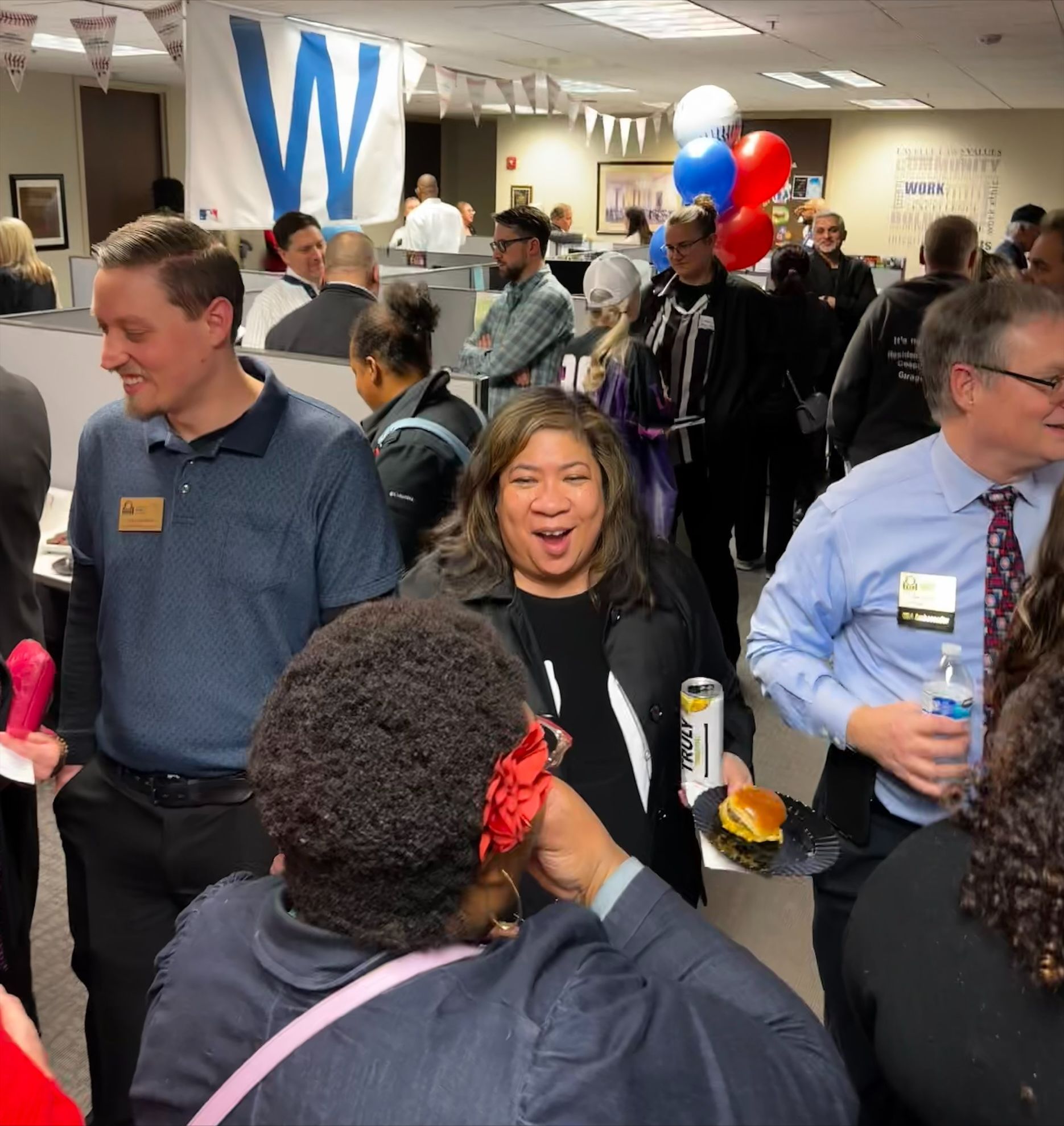 A group of people are gathered in a room with a w flag in the background