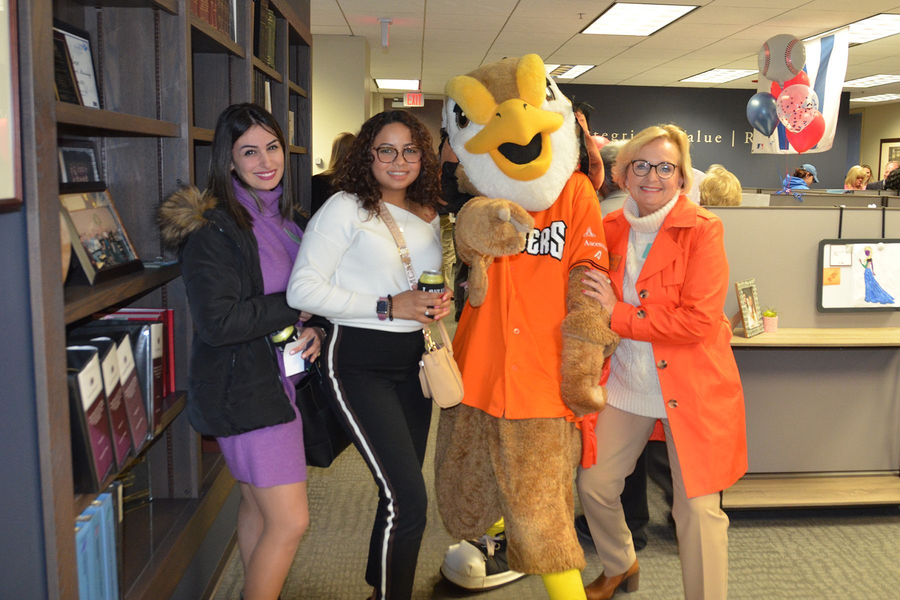 A group of women are posing for a picture with a mascot.