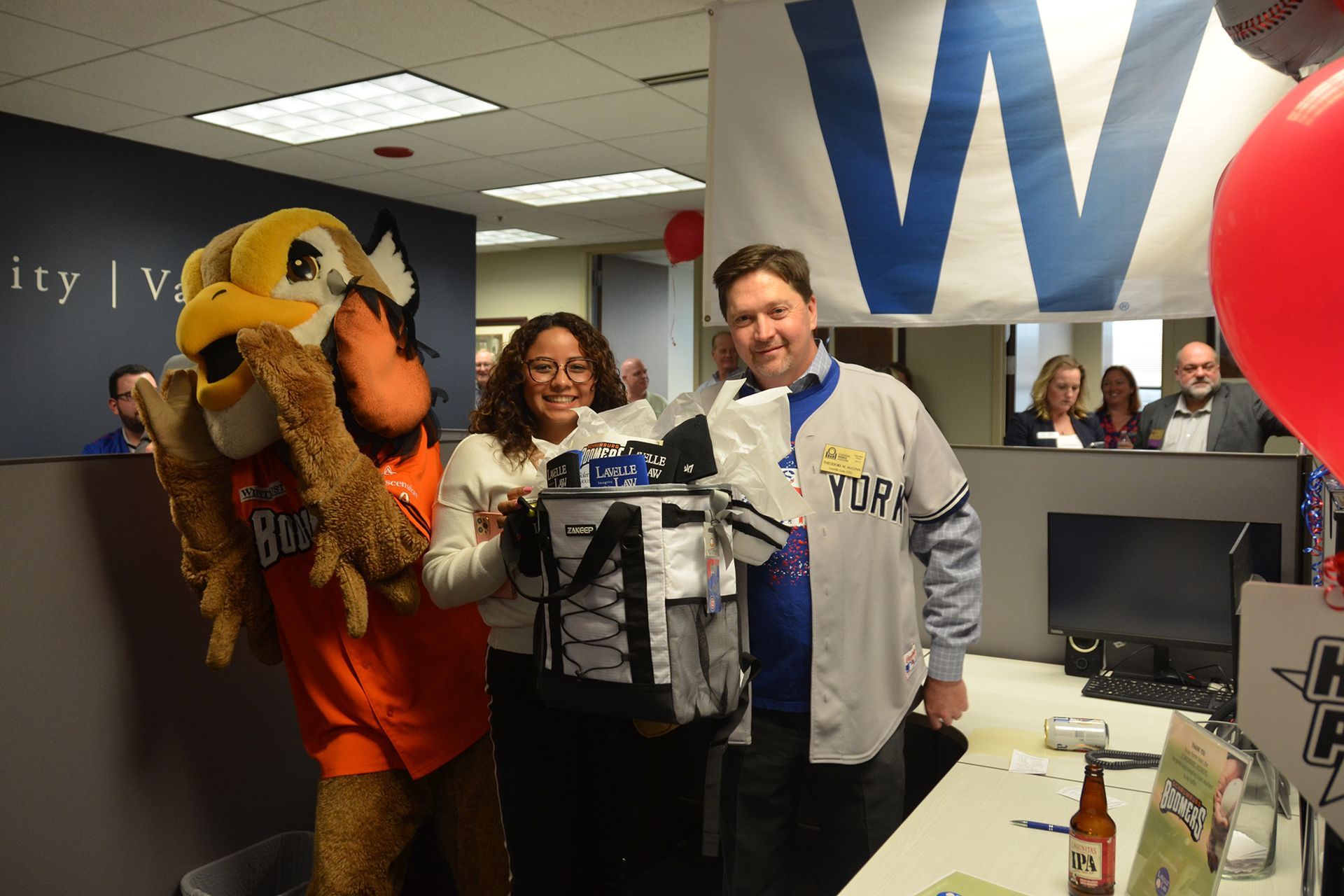 A group of people are posing for a picture with a mascot in an office.