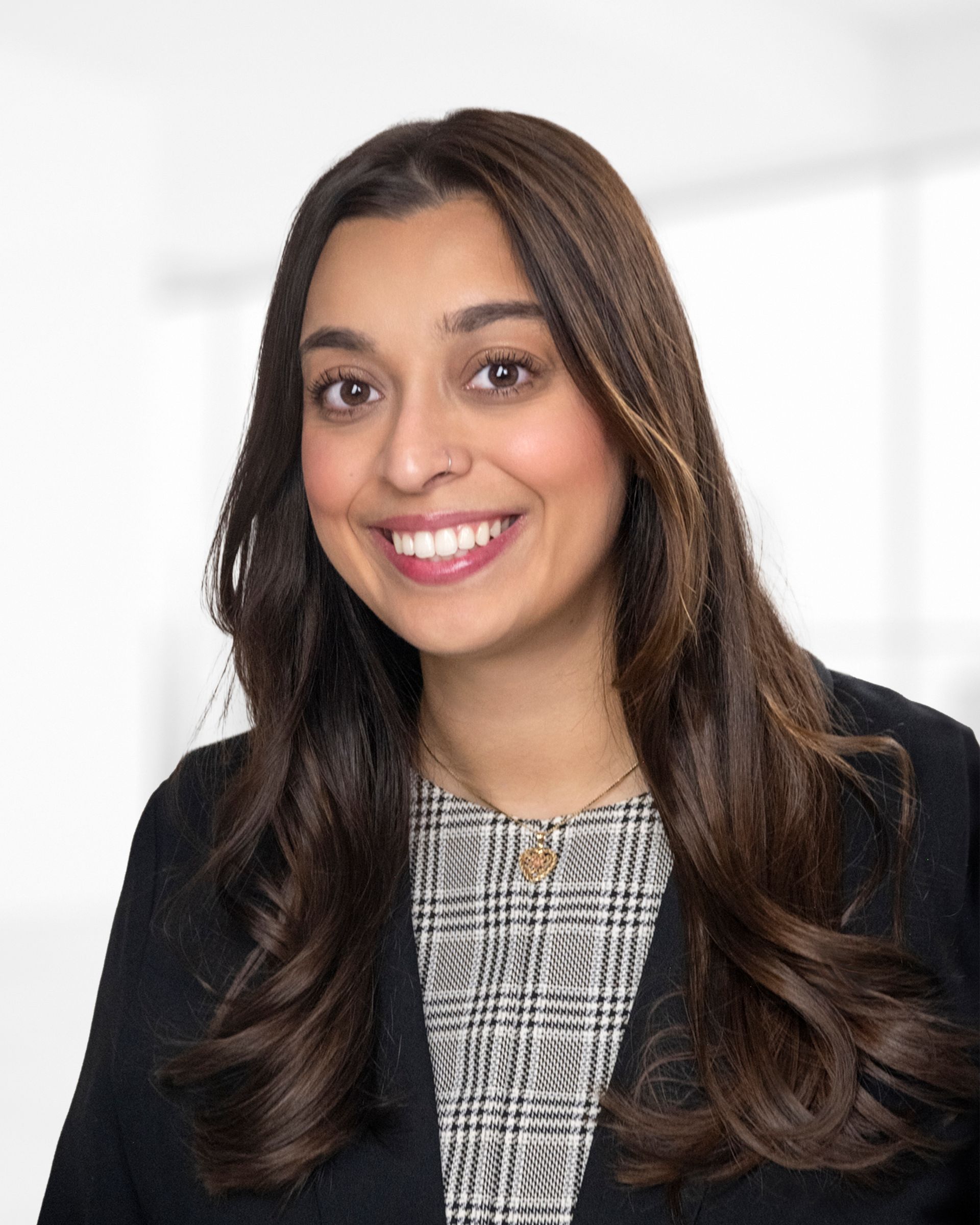 A woman wearing a suit and a pearl necklace smiles for the camera.