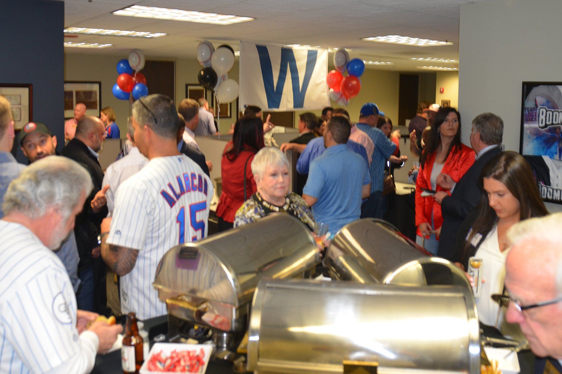 A group of people are gathered in a room with a sign that says w.