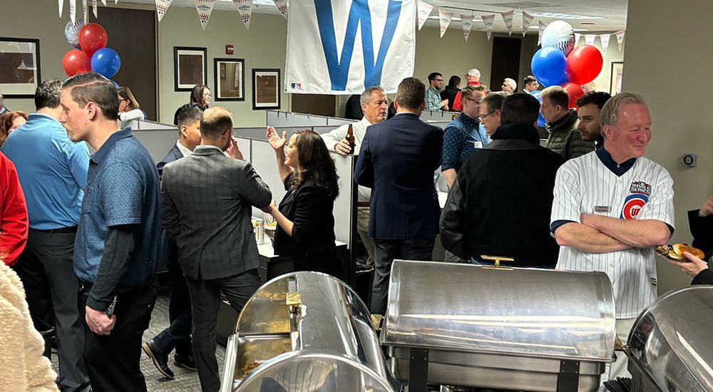 A group of people are standing around a buffet table in a room.