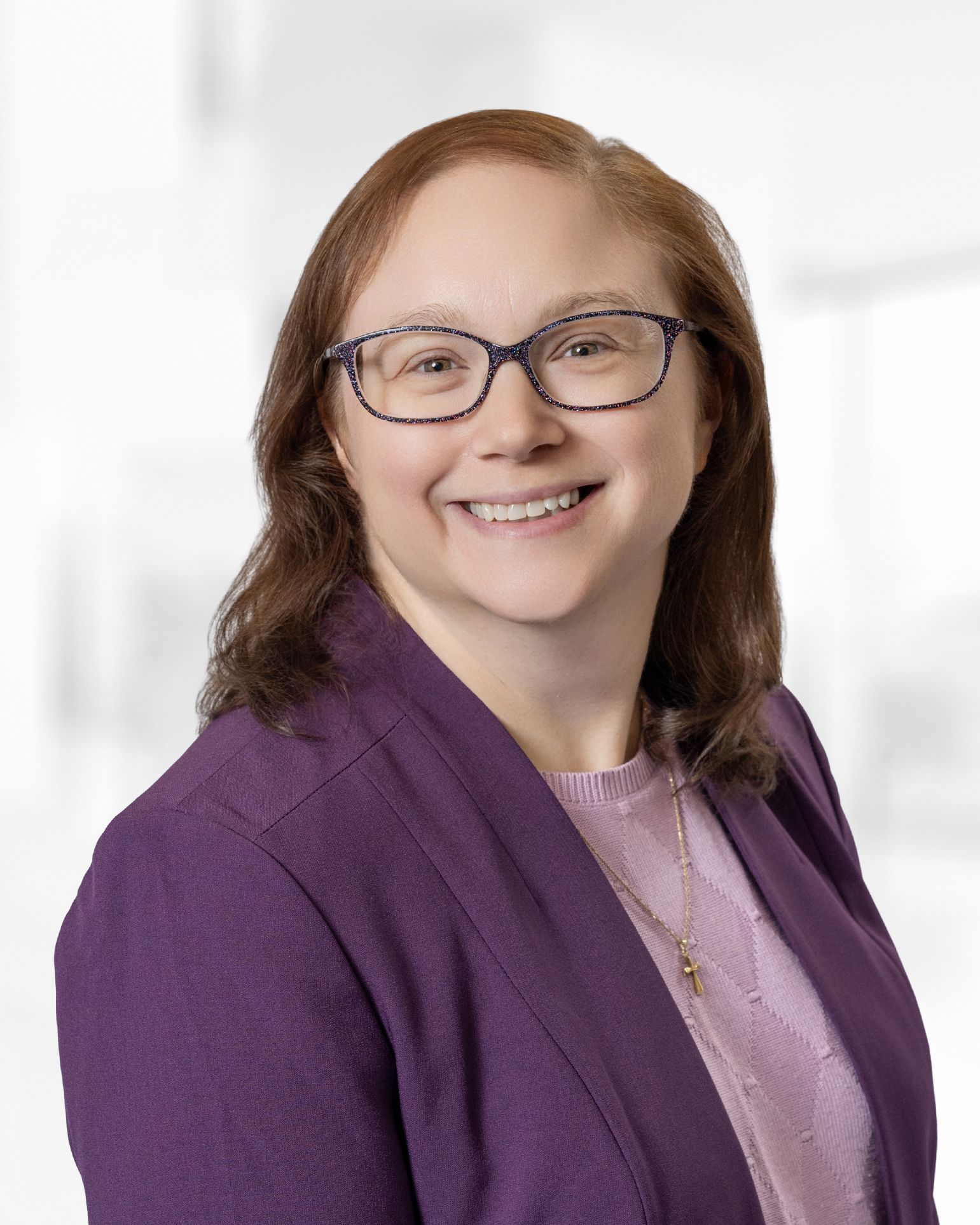 A woman wearing a suit and a pearl necklace smiles for the camera.