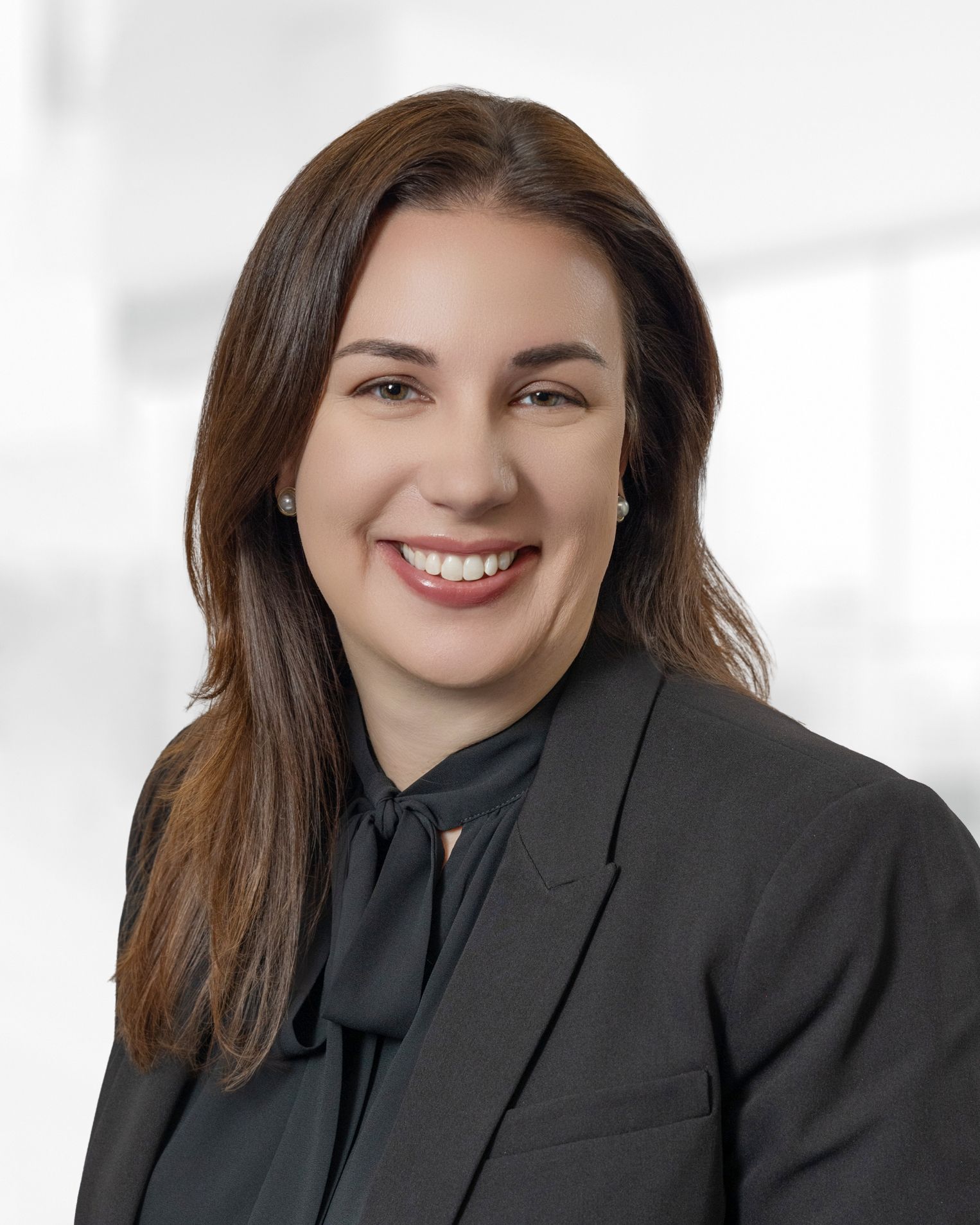 A woman wearing a suit and a pearl necklace smiles for the camera.