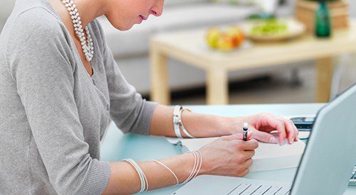 A woman is sitting at a desk using a laptop computer.