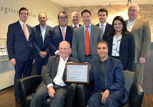 A group of business people are posing for a picture while holding a certificate.