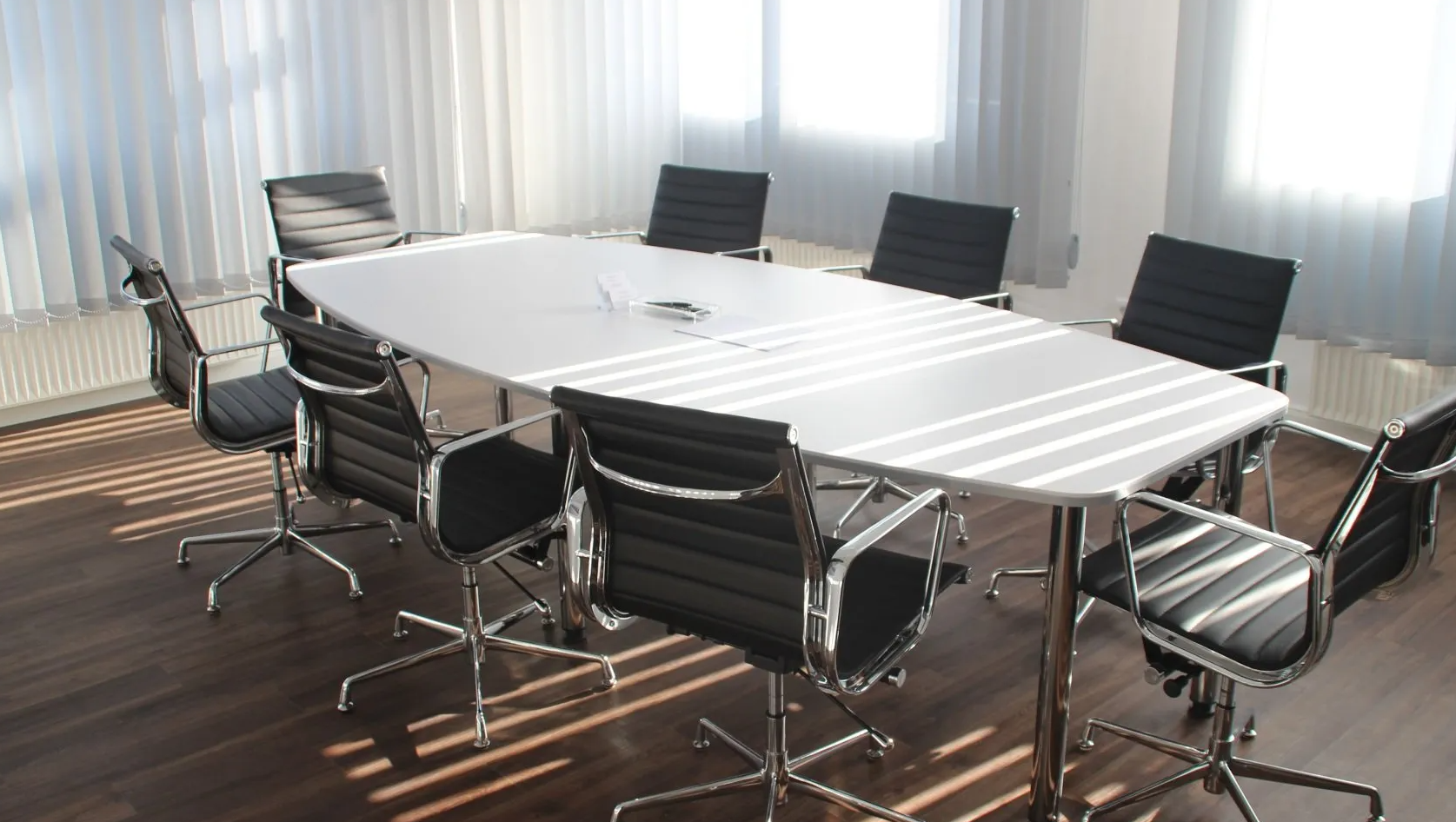 A conference room with a long table and black chairs