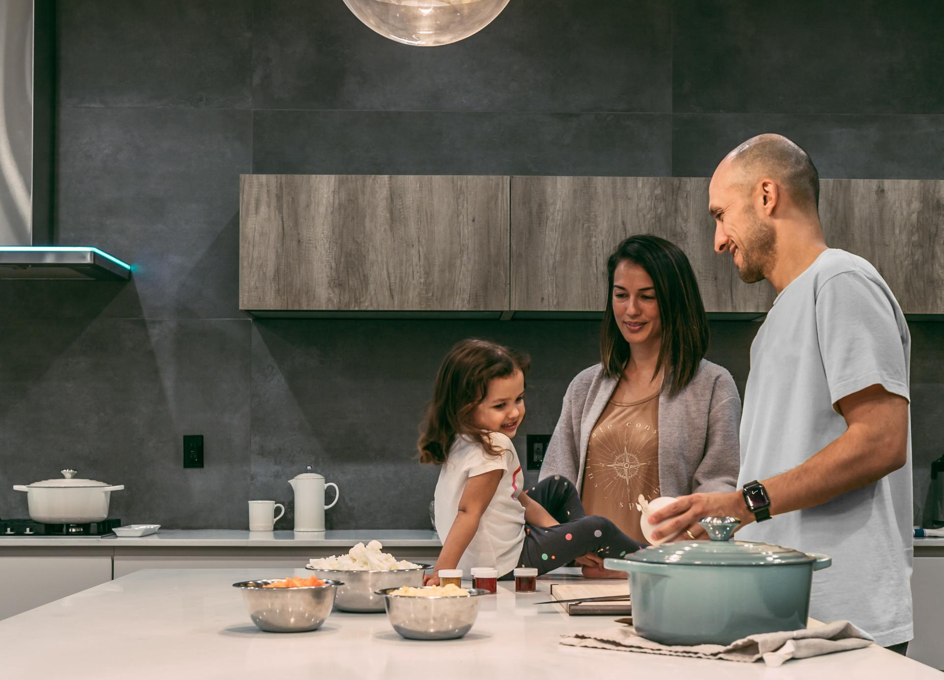 A man , woman and child are standing in a kitchen preparing food.
