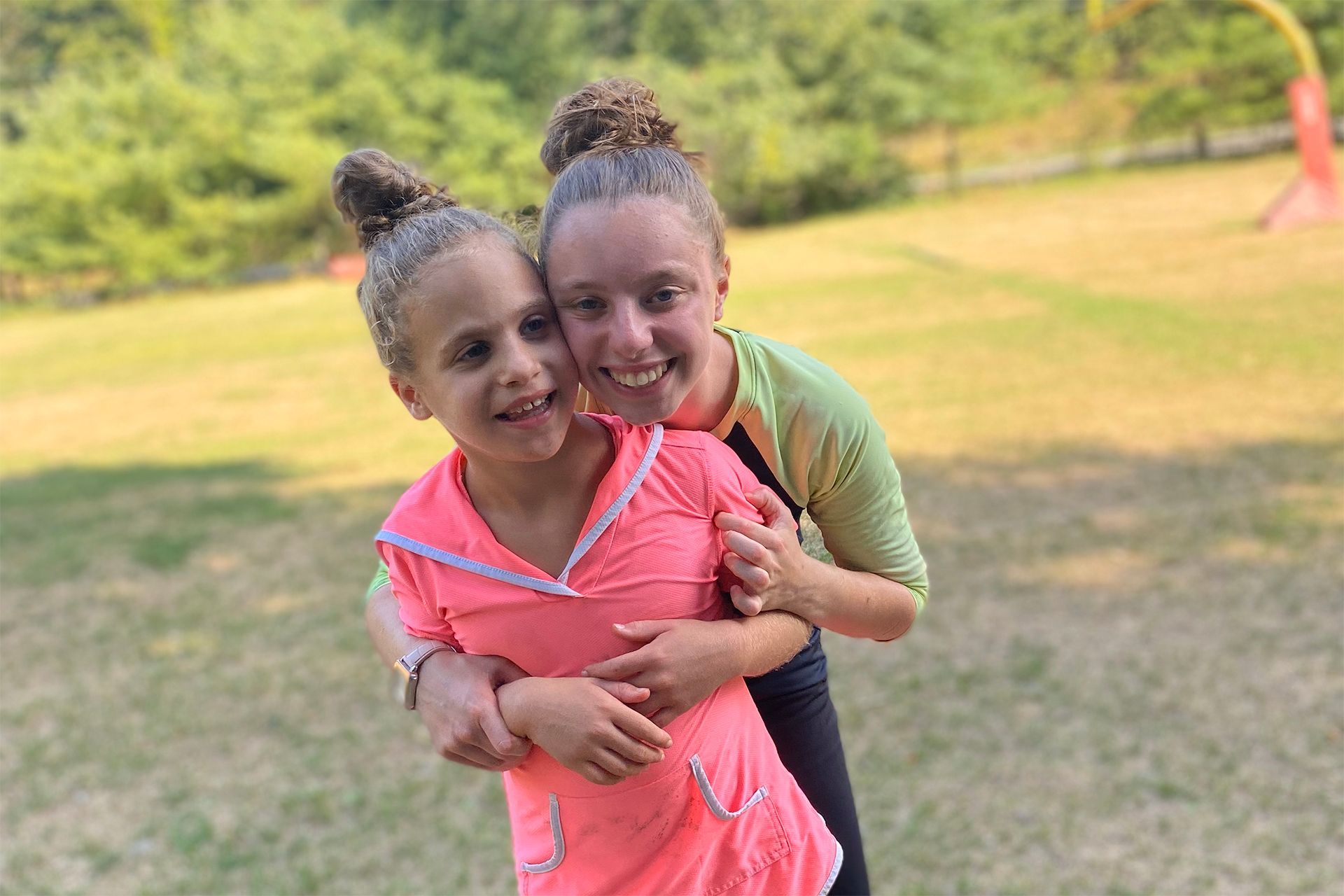 Two girls are posing for a picture in a field.