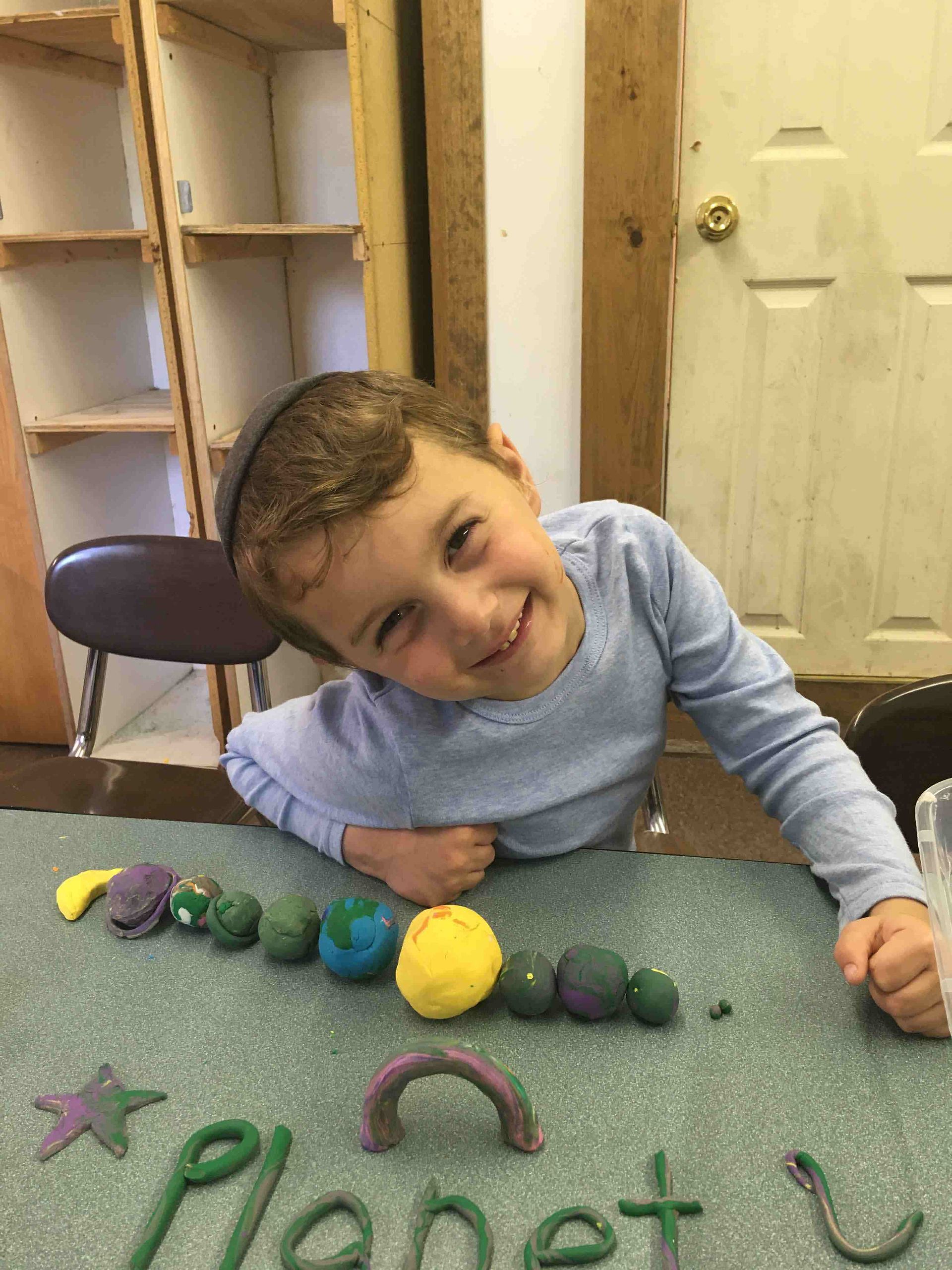 A young boy is sitting at a table with play dough.
