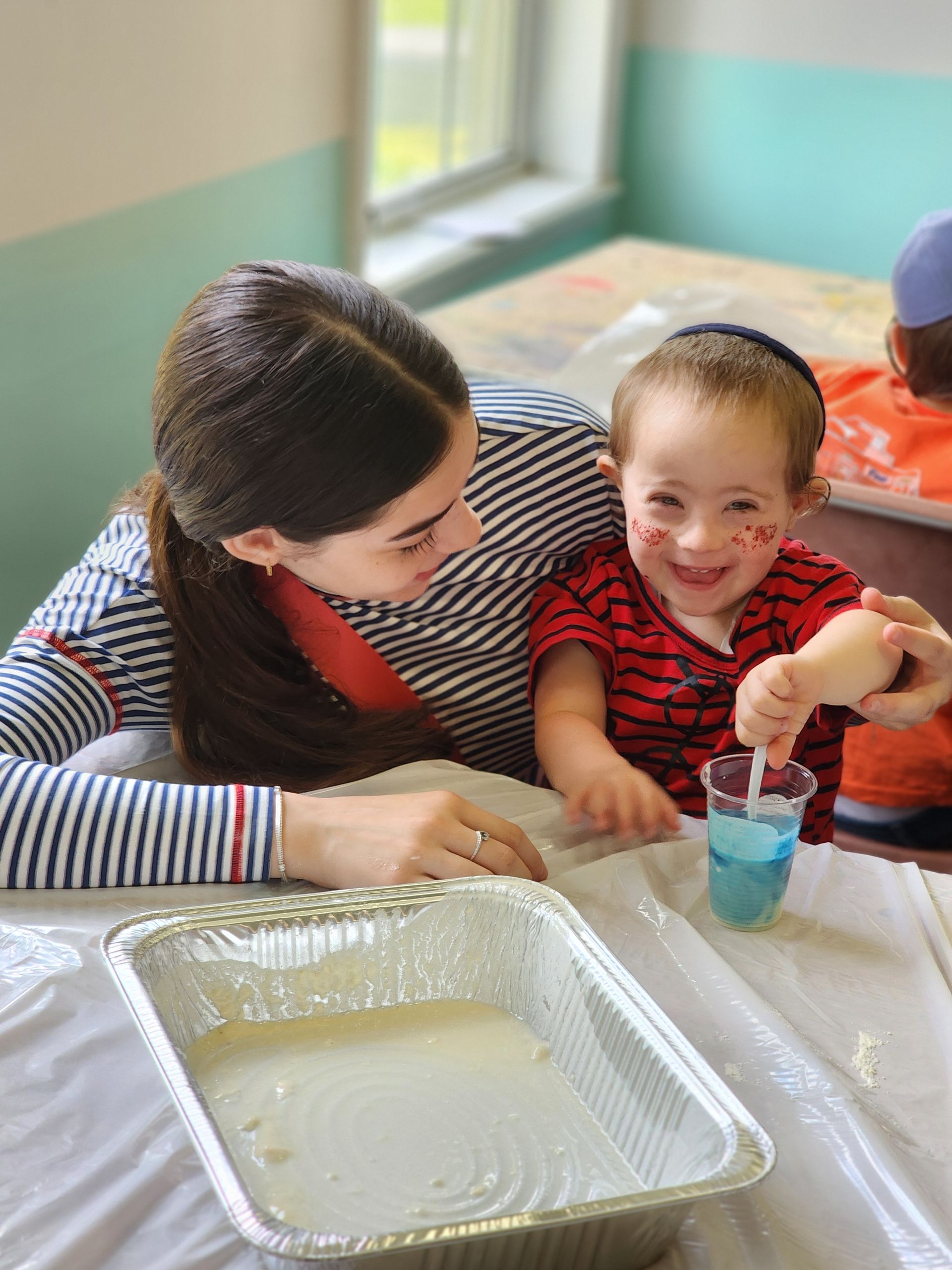 A woman and a child are sitting at a table playing with liquid.