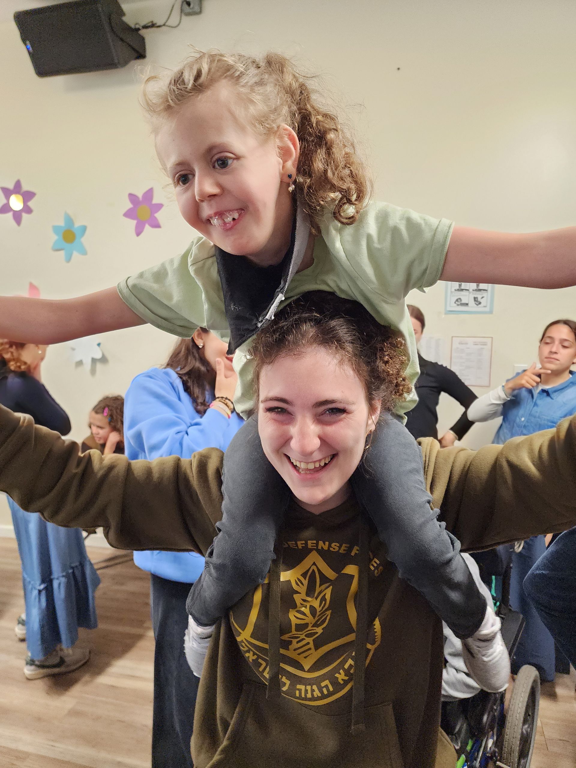 A woman is carrying a little girl on her shoulders.