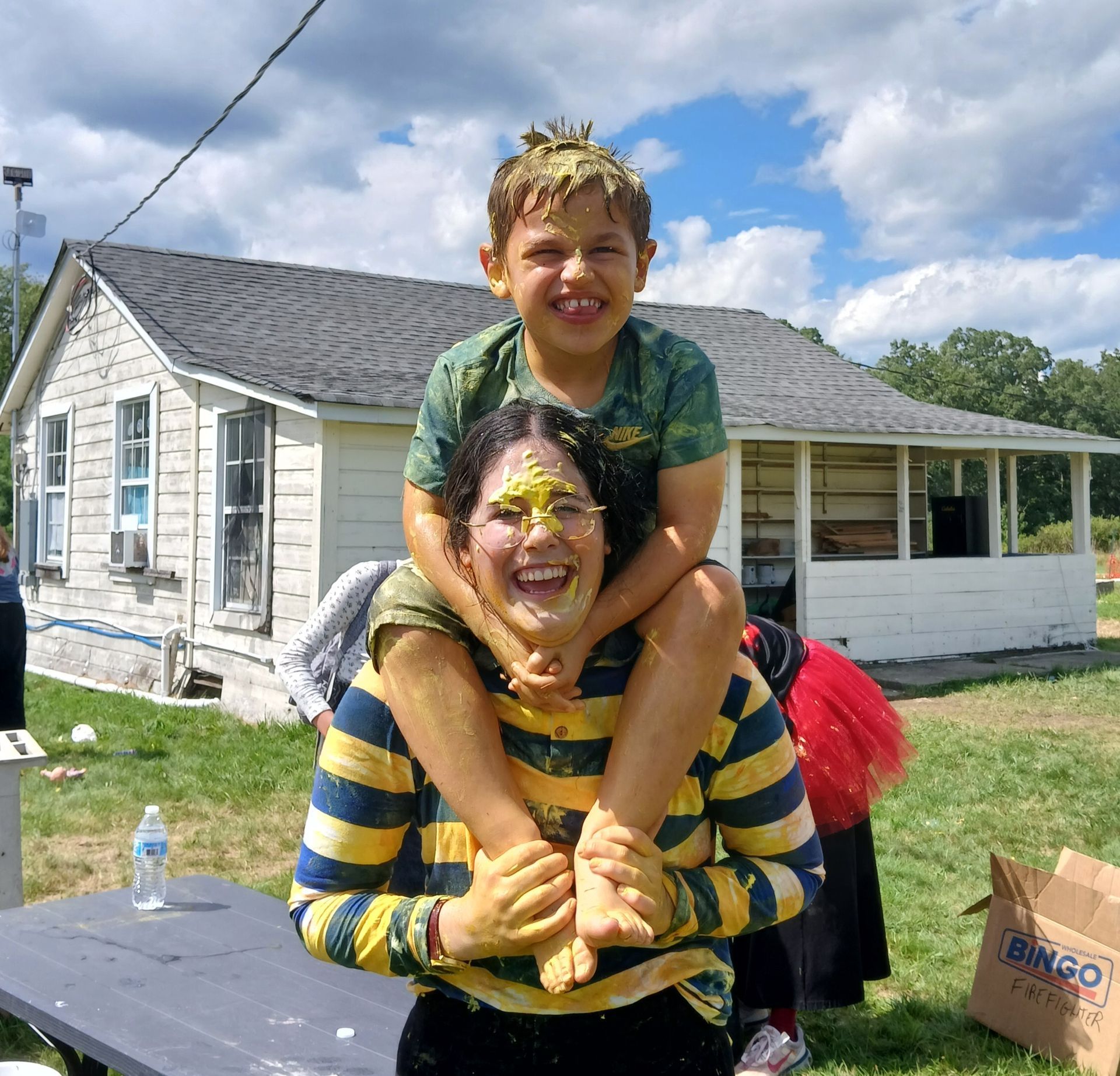 A young boy is sitting on a girl's shoulders and smiling.