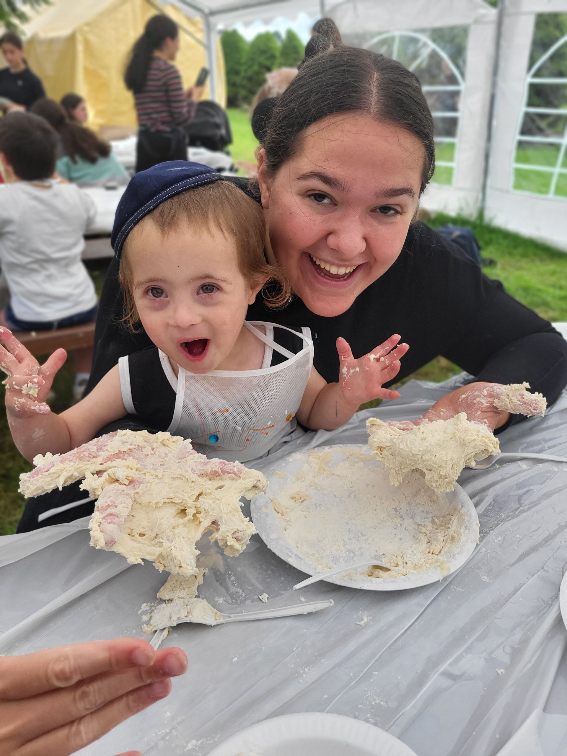 A woman and a little girl are sitting at a table with food on it.