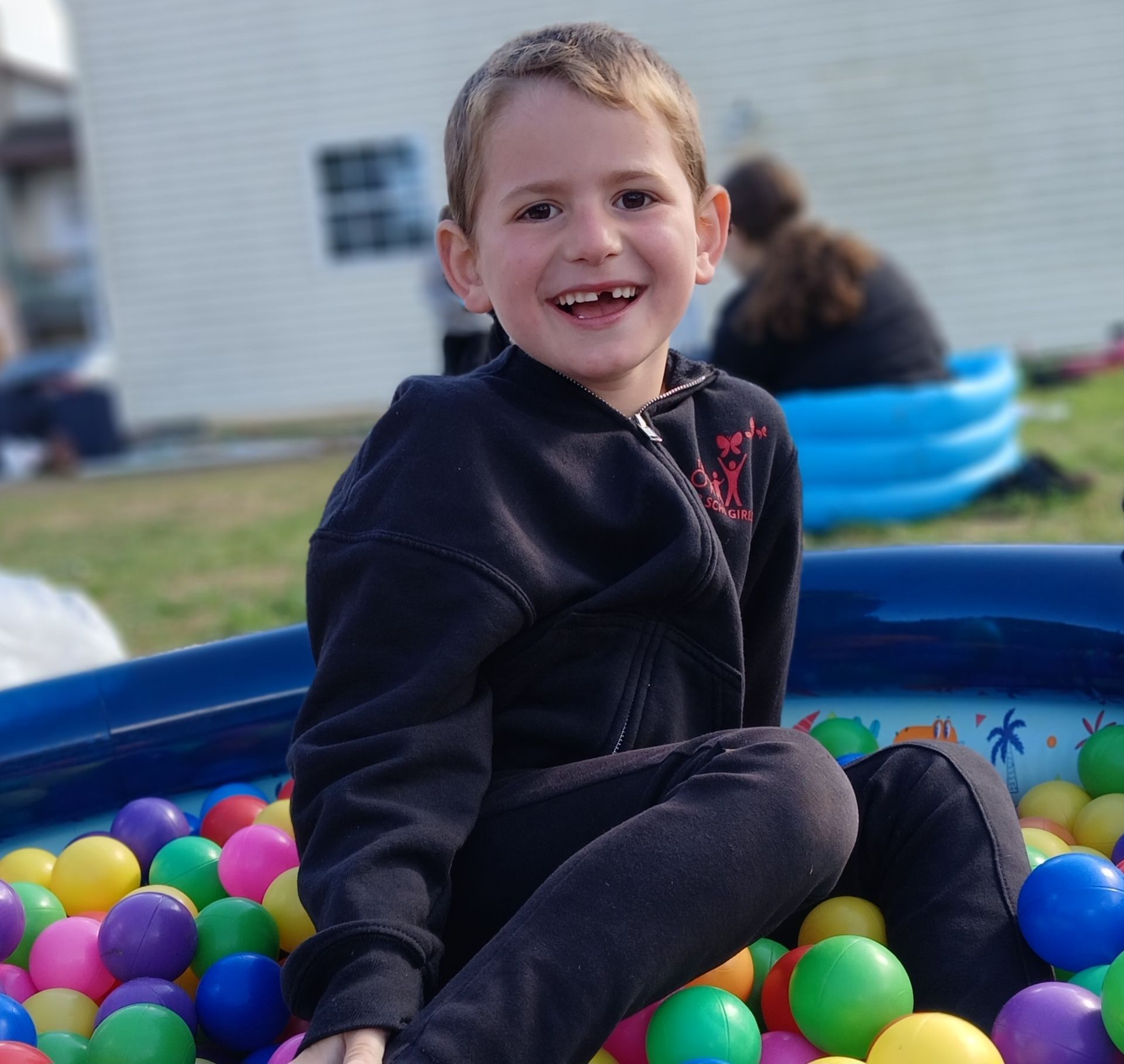 A little boy is sitting in a pool of colorful balls
