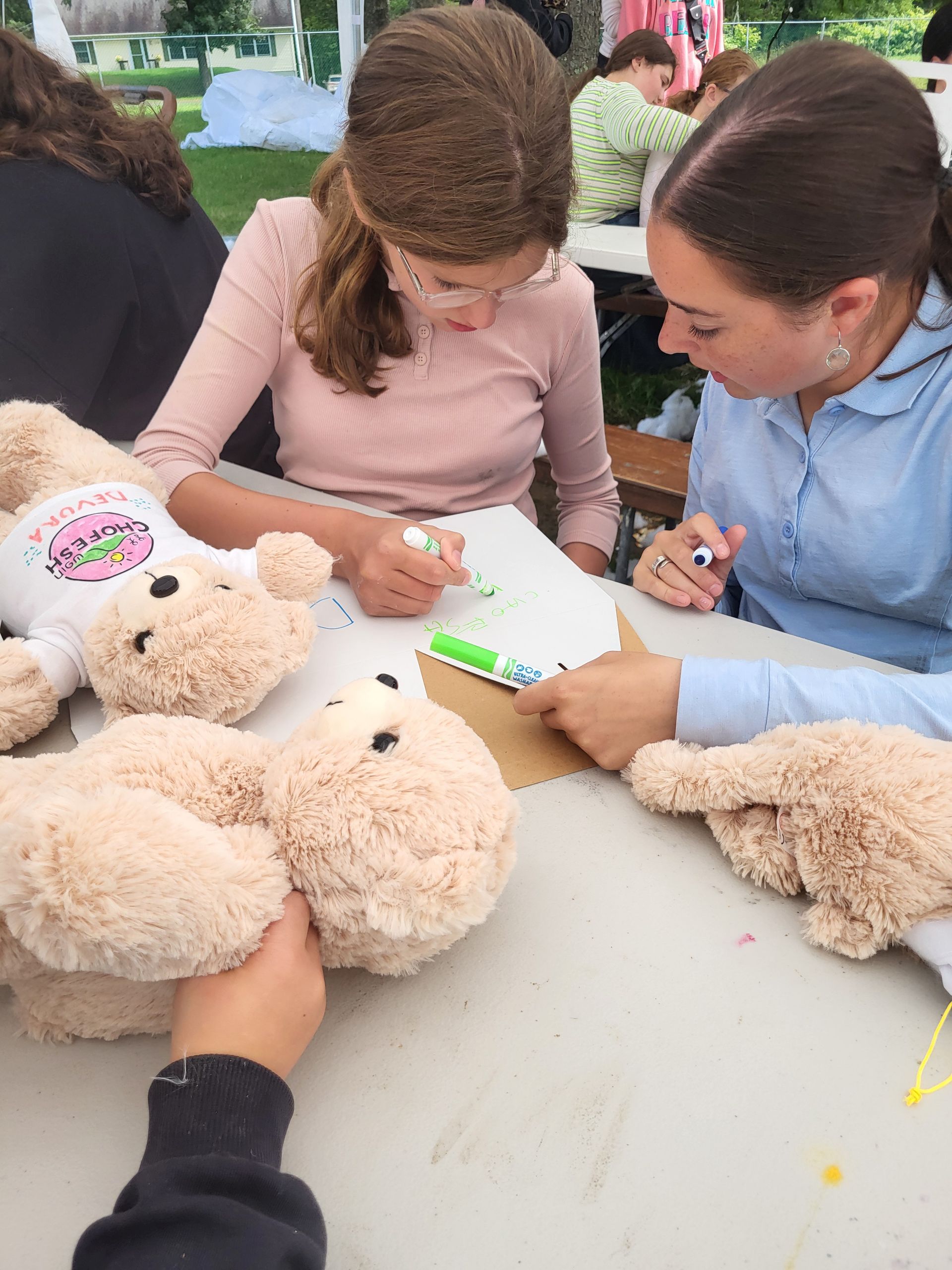 A group of people are sitting at a table with stuffed animals